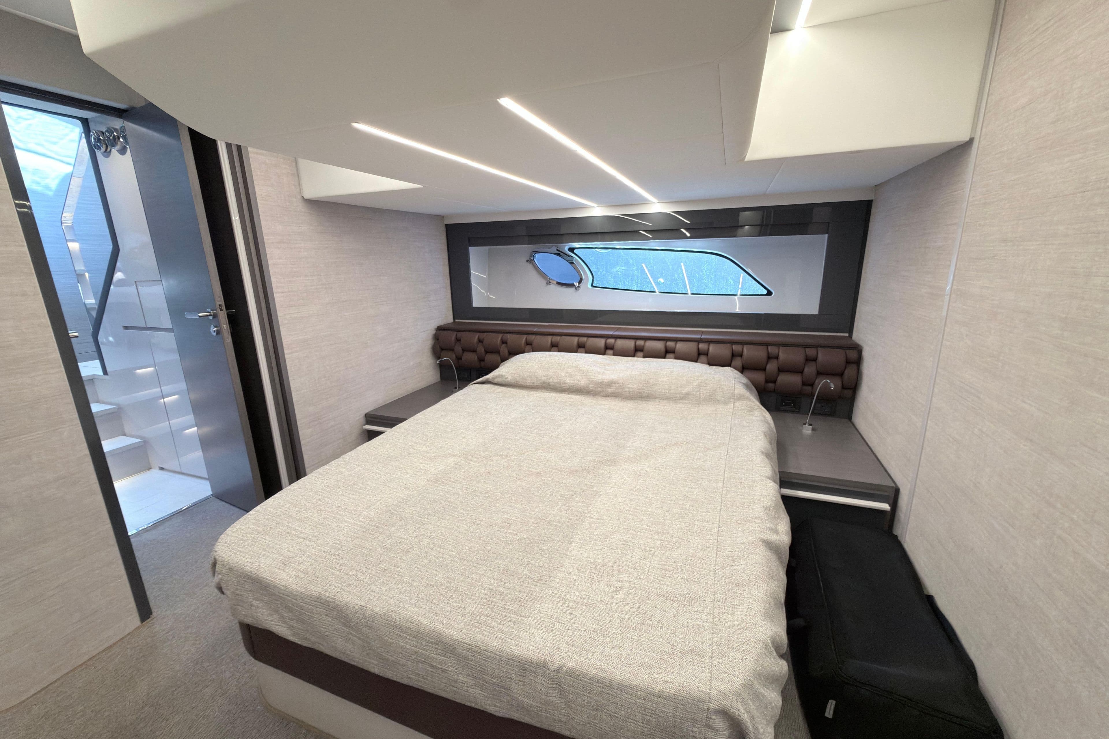 Luxurious bedroom interior of 2023 Pershing 5x yacht with modern design and window view.