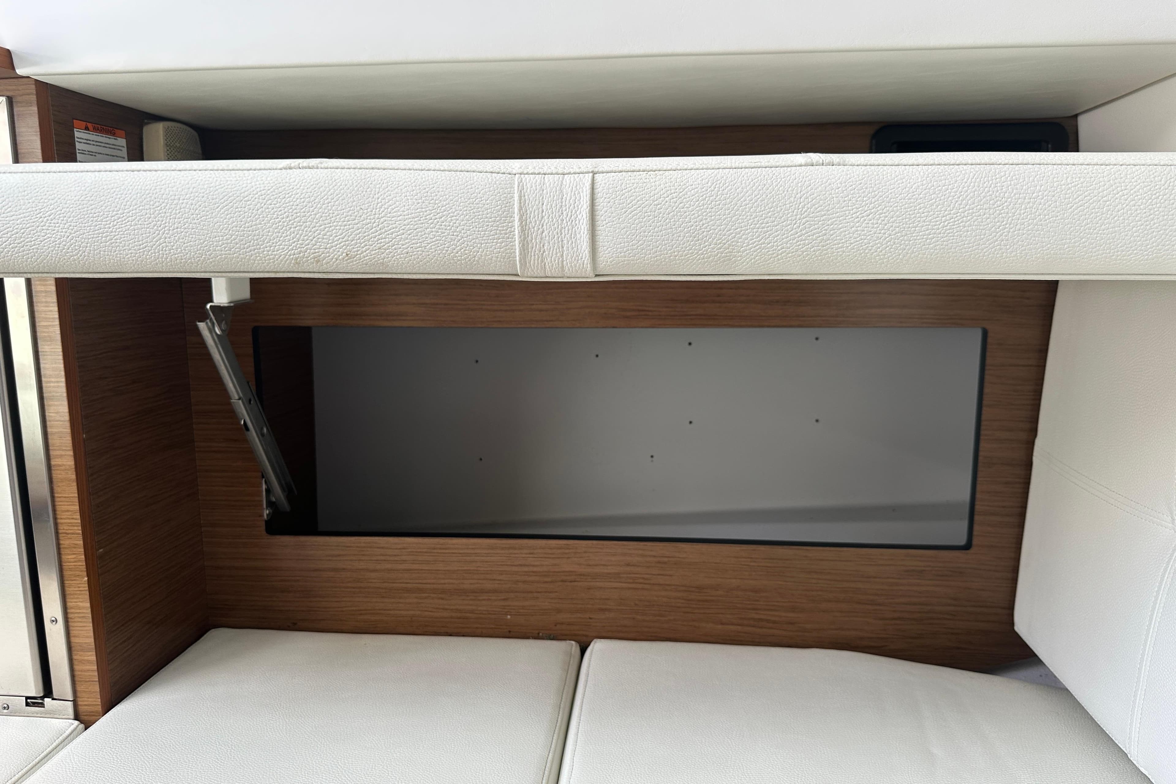 2019 Cruisers Yachts 338 Outboard interior storage compartment with white cushioned seating.