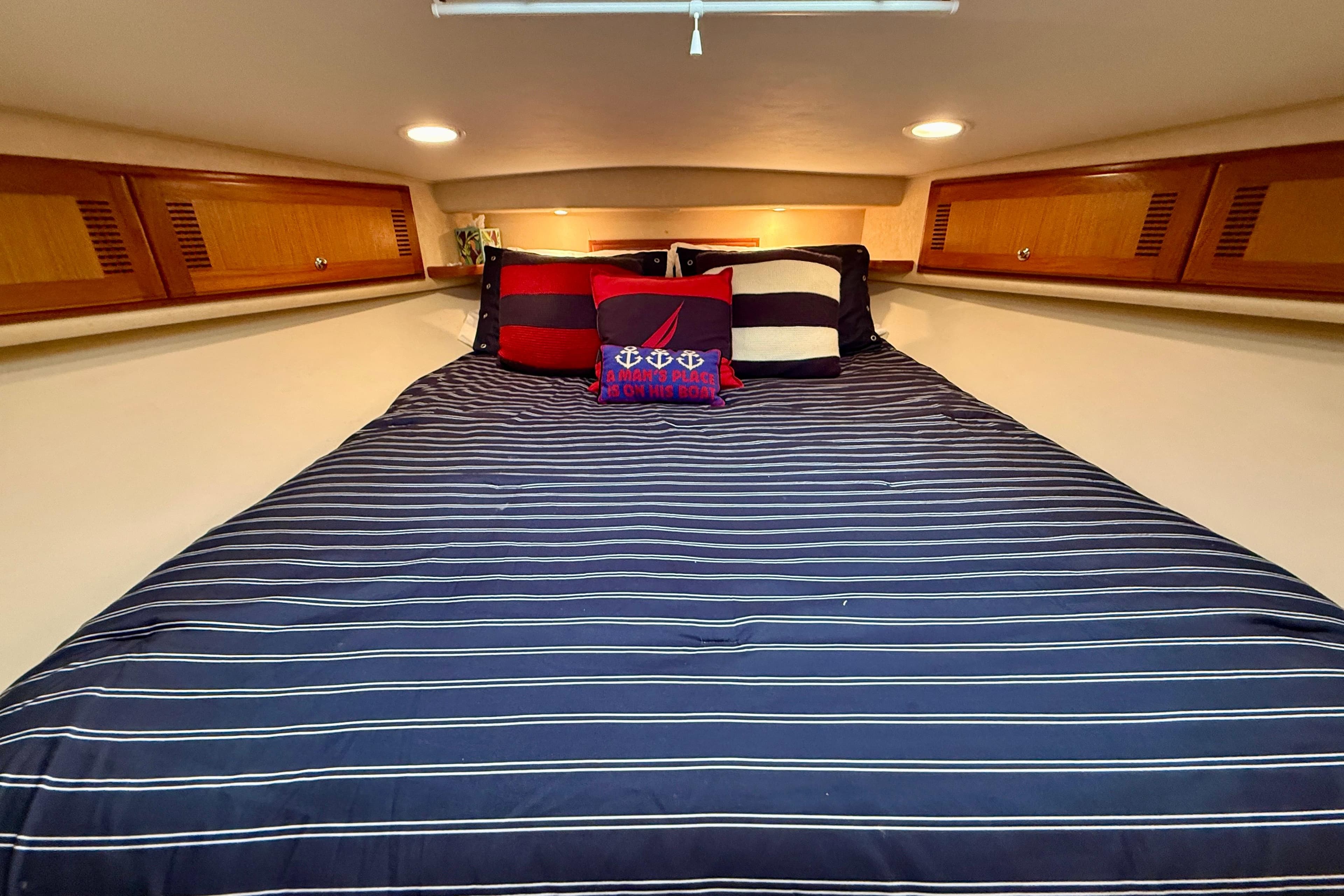Luxurious cabin interior of 2006 Cabo 40 Flybridge yacht with striped bedding.