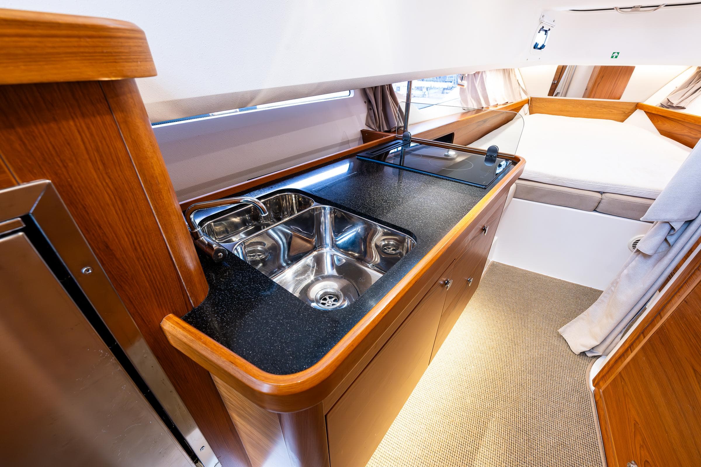 Luxurious Nimbus C11 2021 yacht interior with modern kitchenette and cozy sleeping area.