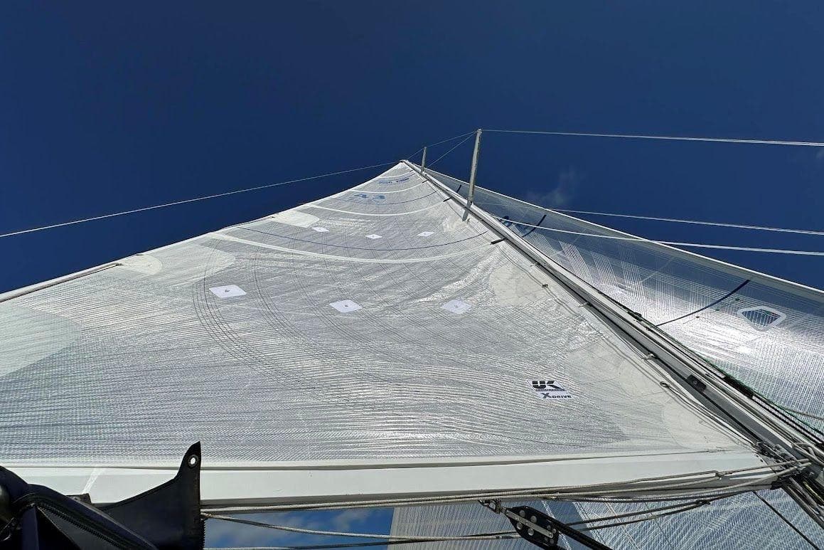 Sail of 1985 C&C 332 Sloop against clear blue sky.