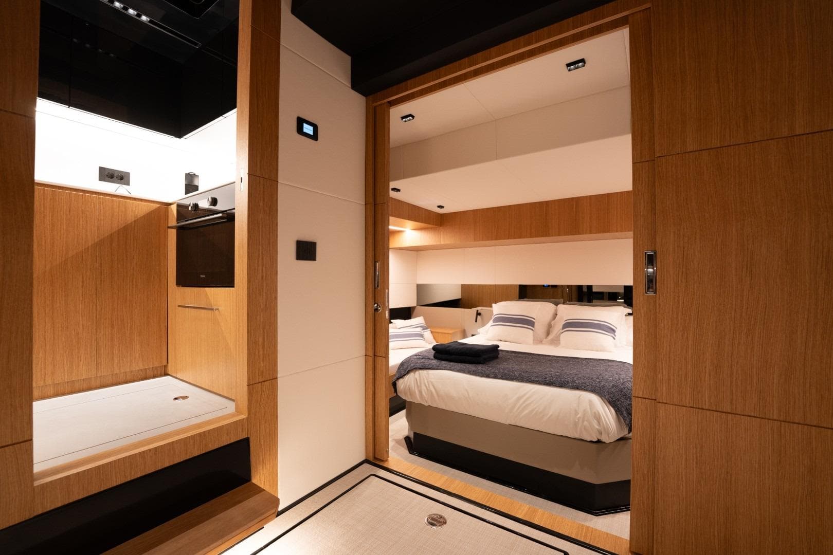 Luxurious interior of 2026 De Antonio Yachts D60, featuring a cozy bedroom and modern kitchen.