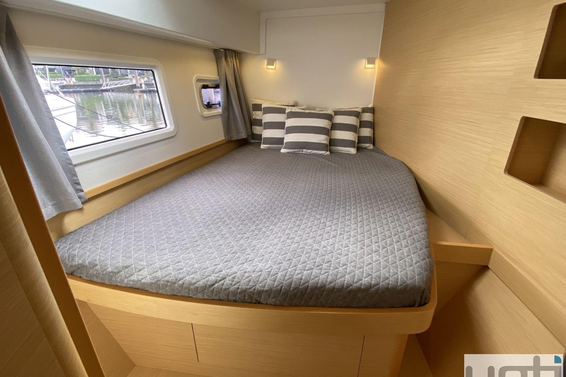 Cozy cabin interior of 2017 Lagoon 42 catamaran with striped pillows and window view.