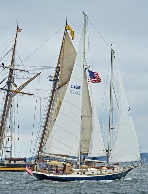 Cherubini Schooner 2000 sailing with American flag on a cloudy day.