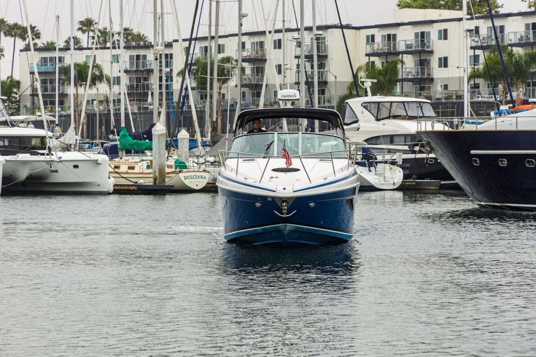 2014 Regal 32 Express boat navigating a marina, surrounded by sailboats and yachts.