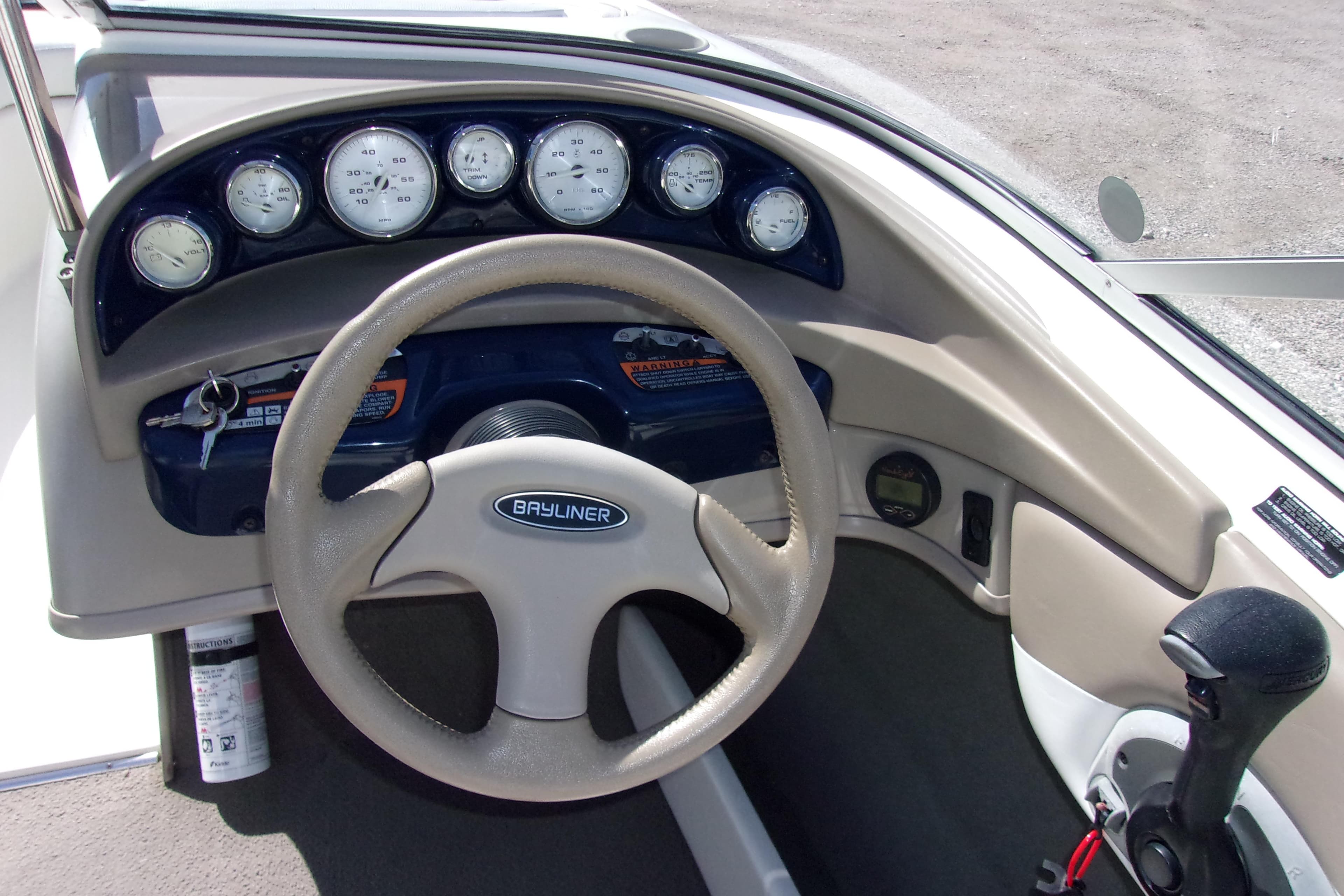 Dashboard of a 2003 Bayliner 205 boat with steering wheel and gauges.