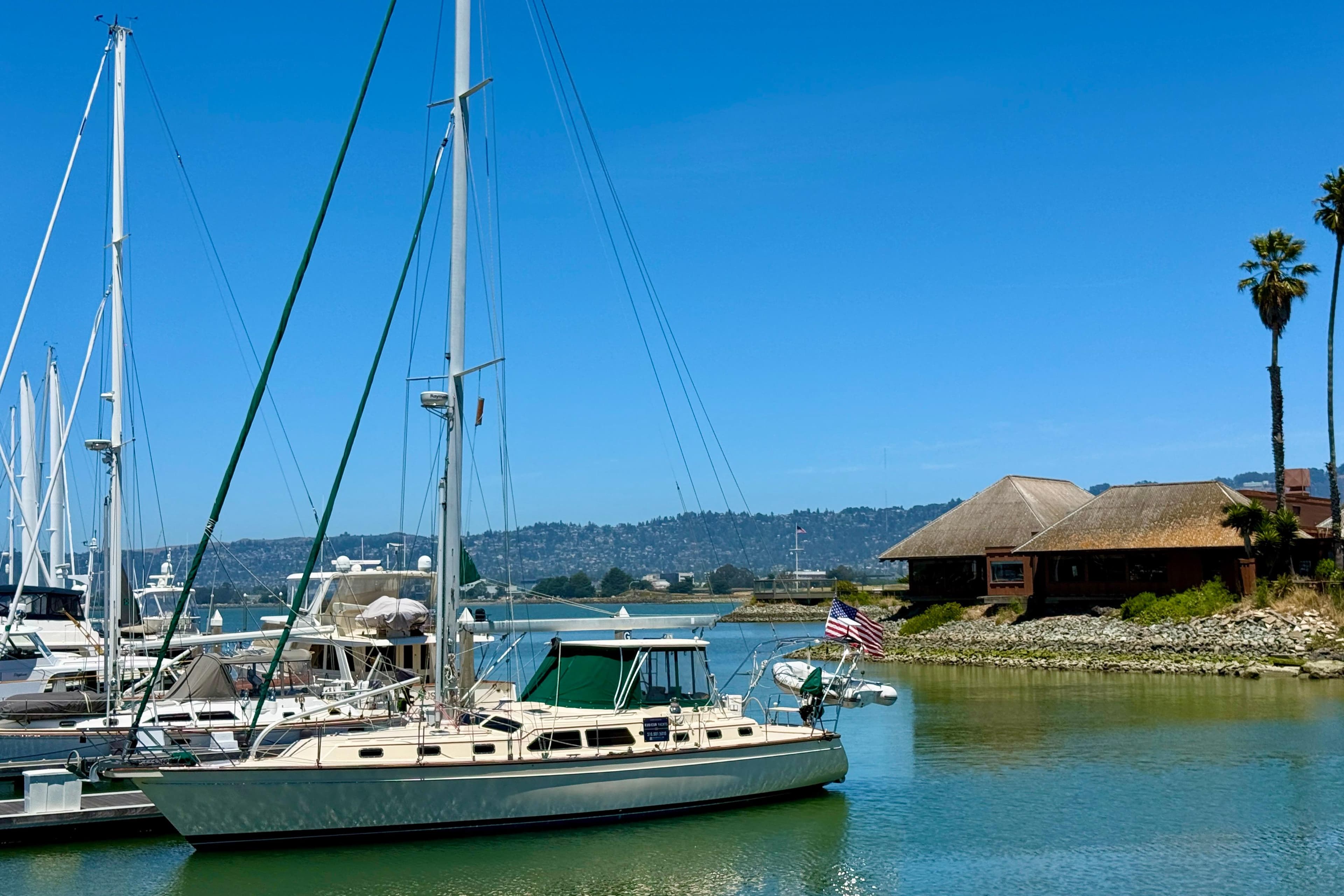 Island Packet 485 sailboat docked in a serene marina, clear blue sky, 2003 model.