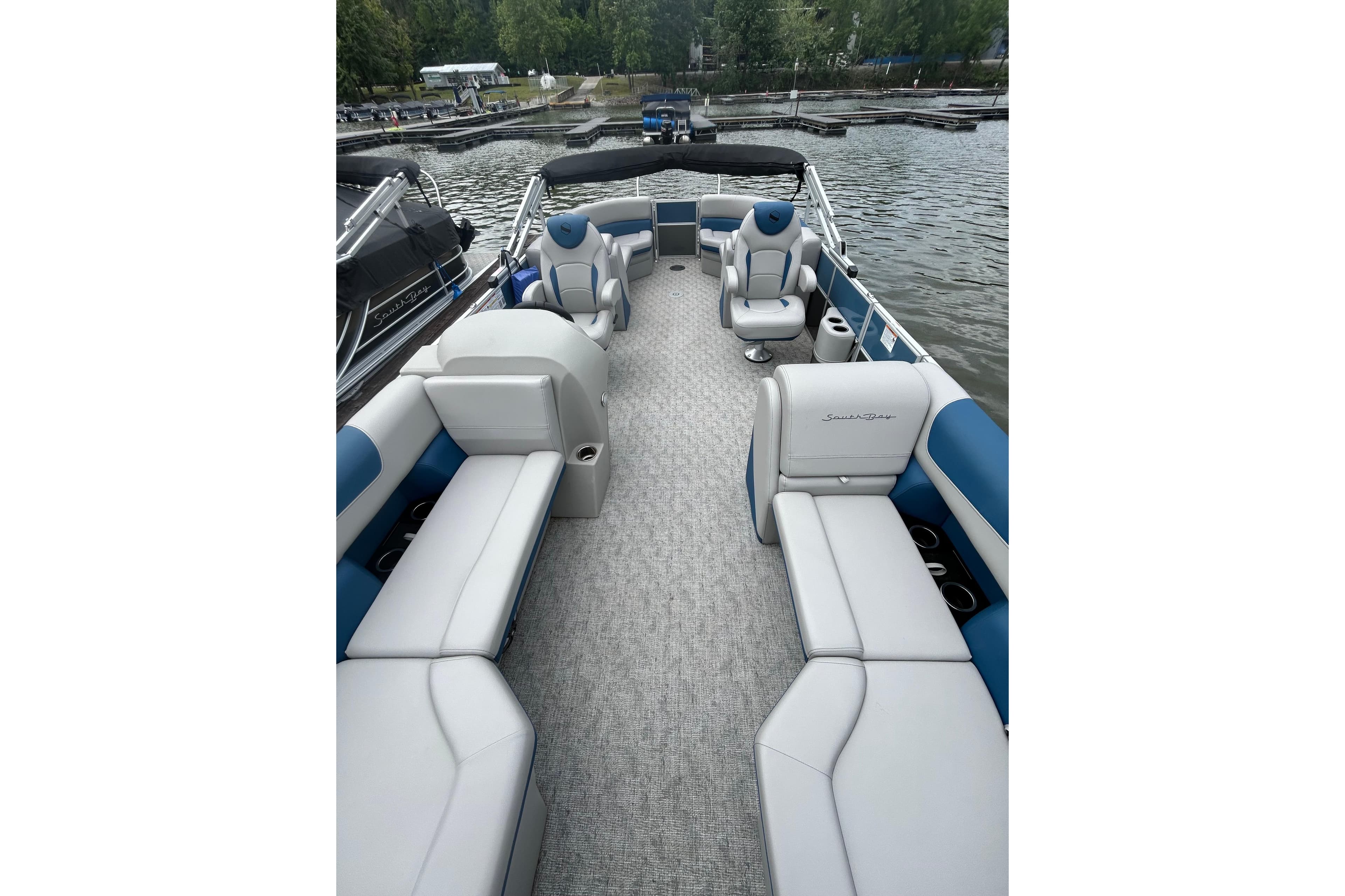 2025 Southbay 224RSLE25 pontoon boat interior with plush seating on a serene lake.