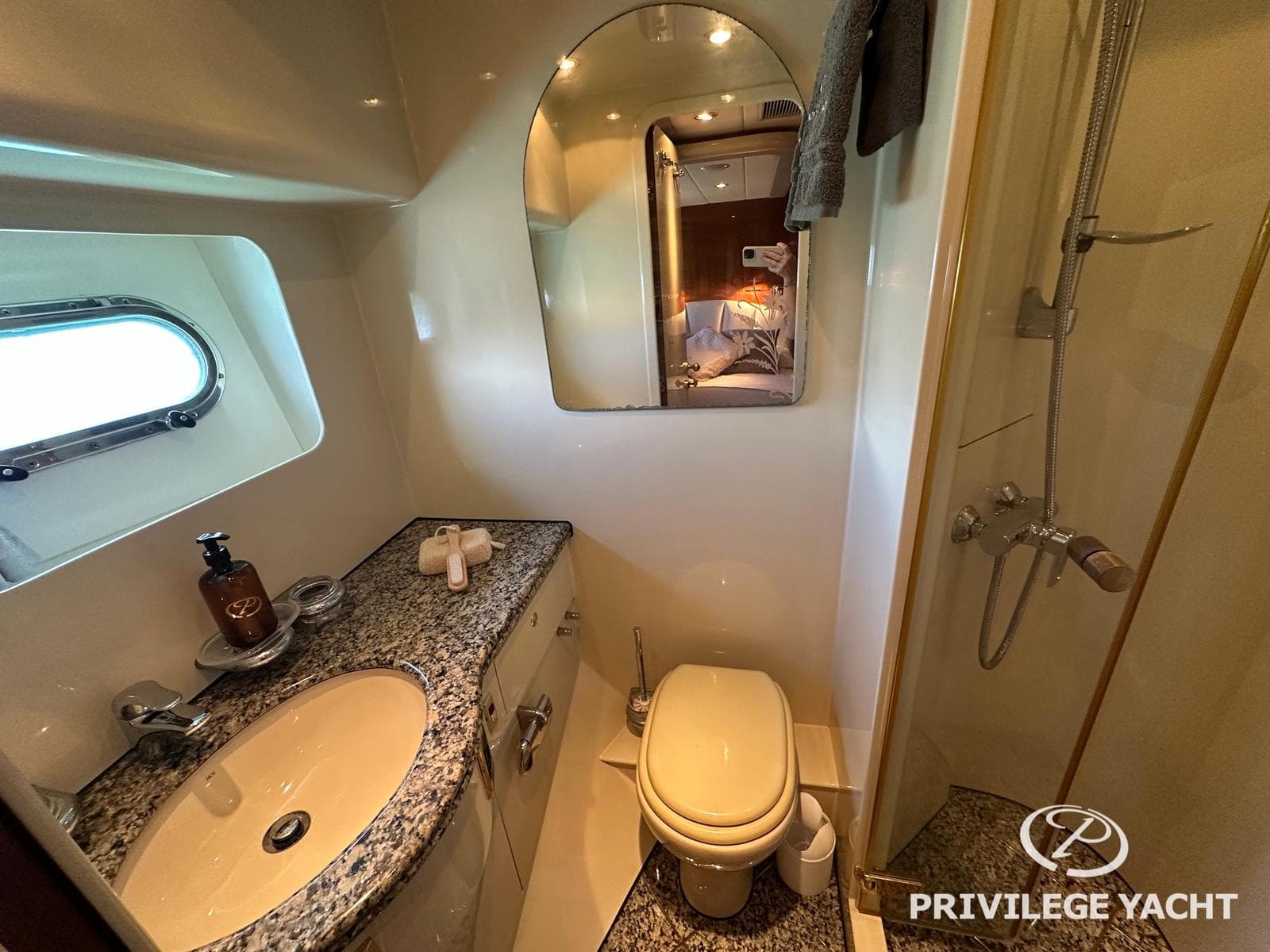 Luxurious yacht bathroom with granite countertop, shower, and porthole window. Elegance 76, 2003 model.