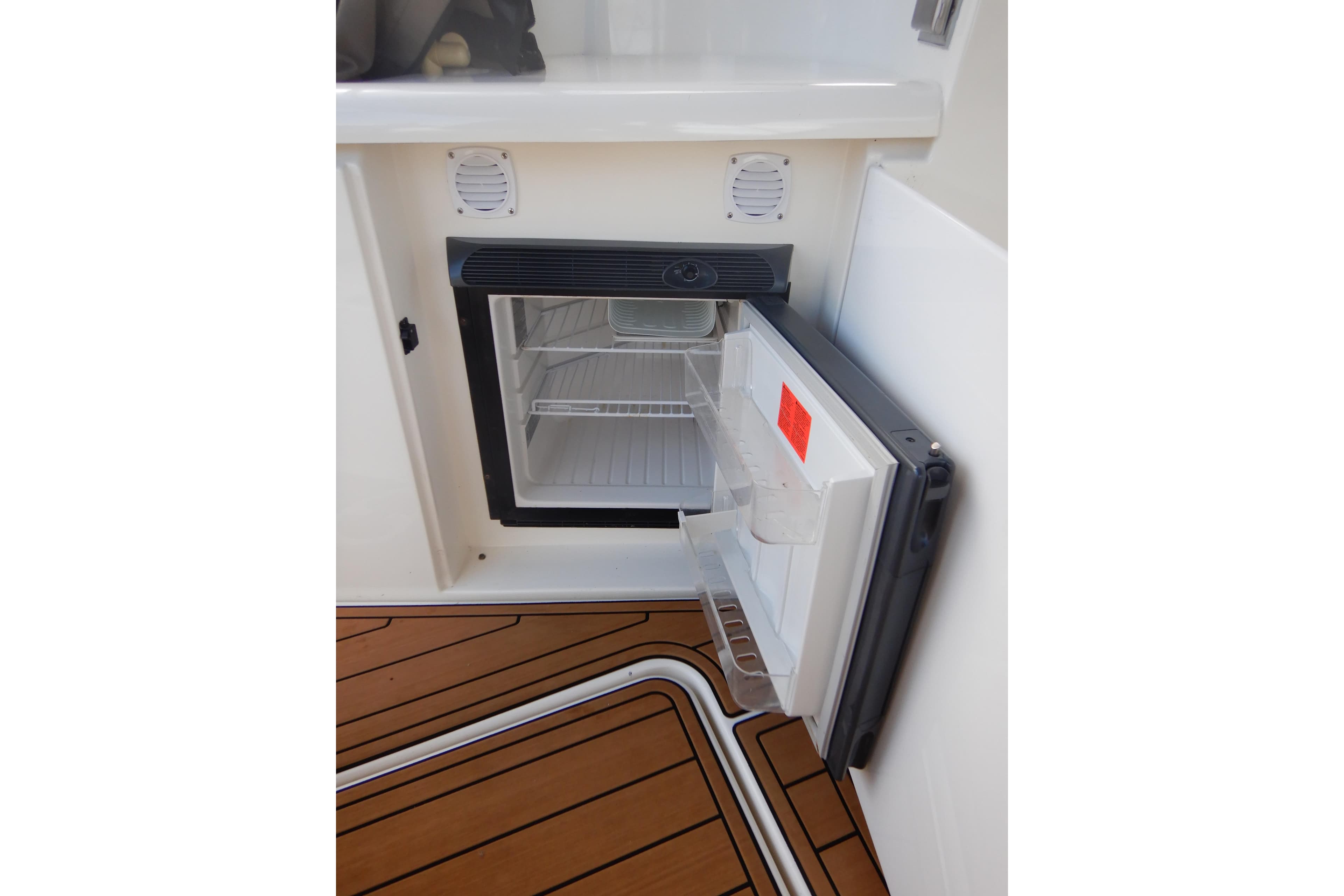 Open mini fridge on 2007 Cruisers 340 Express boat with teak flooring.