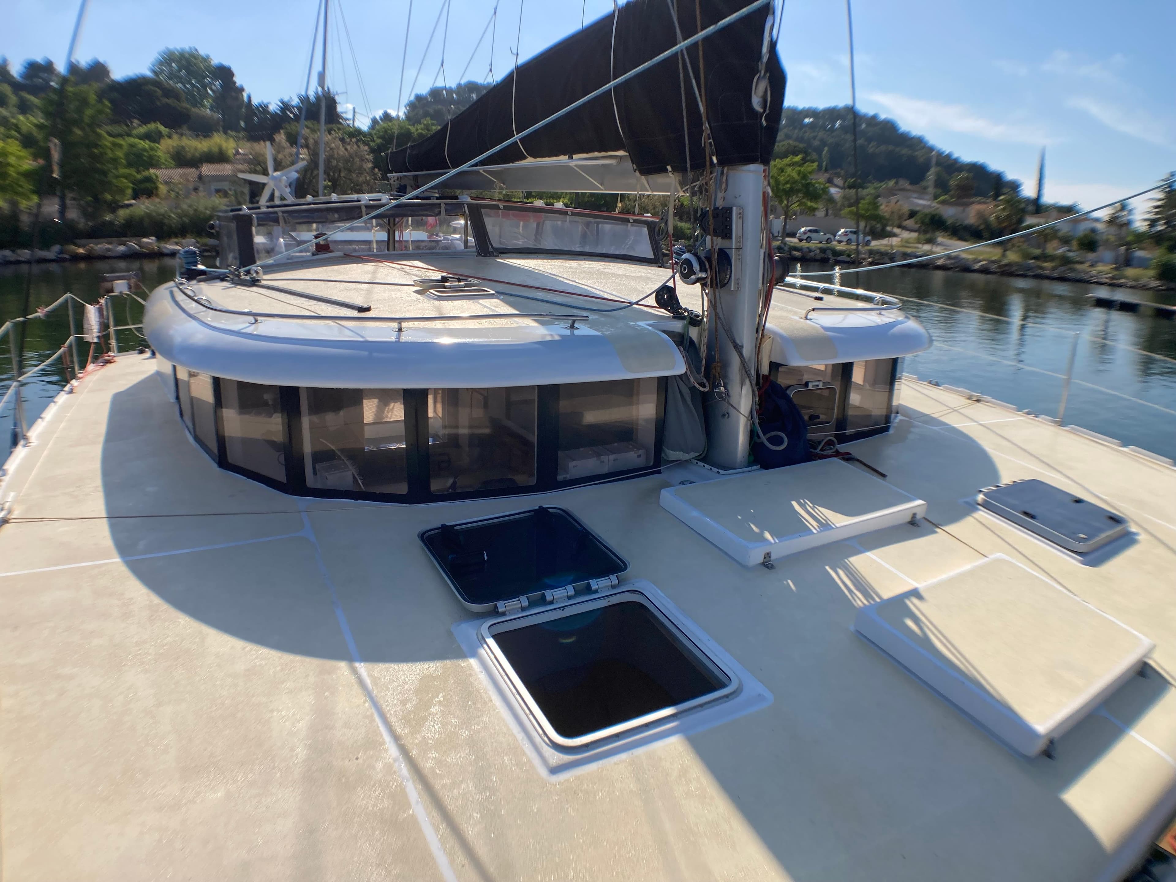 Custom catamaran 15M, 2000 model, docked with open hatches and scenic background.