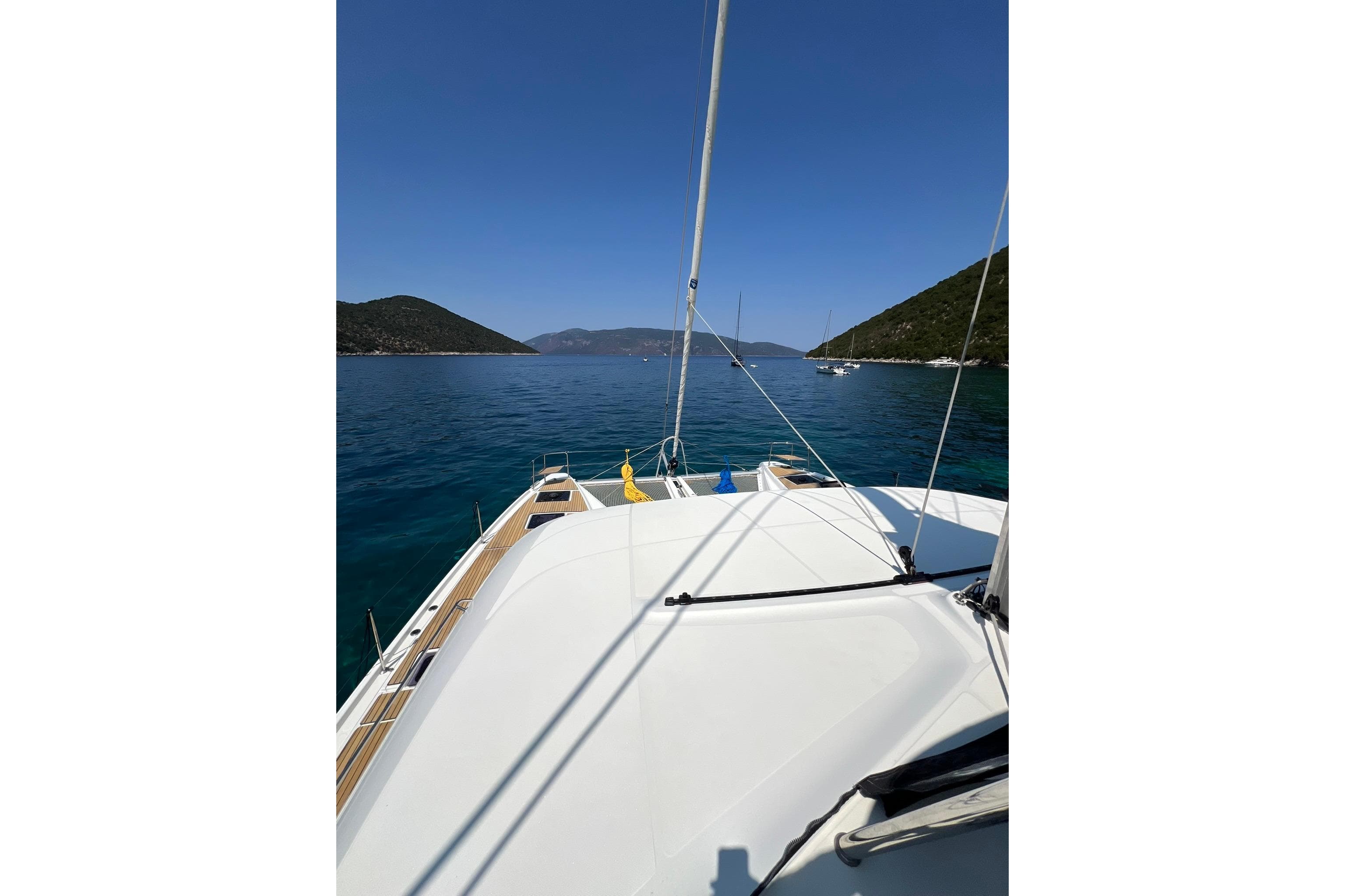 Front deck view of 2020 Lagoon 50 catamaran sailing in clear blue waters.