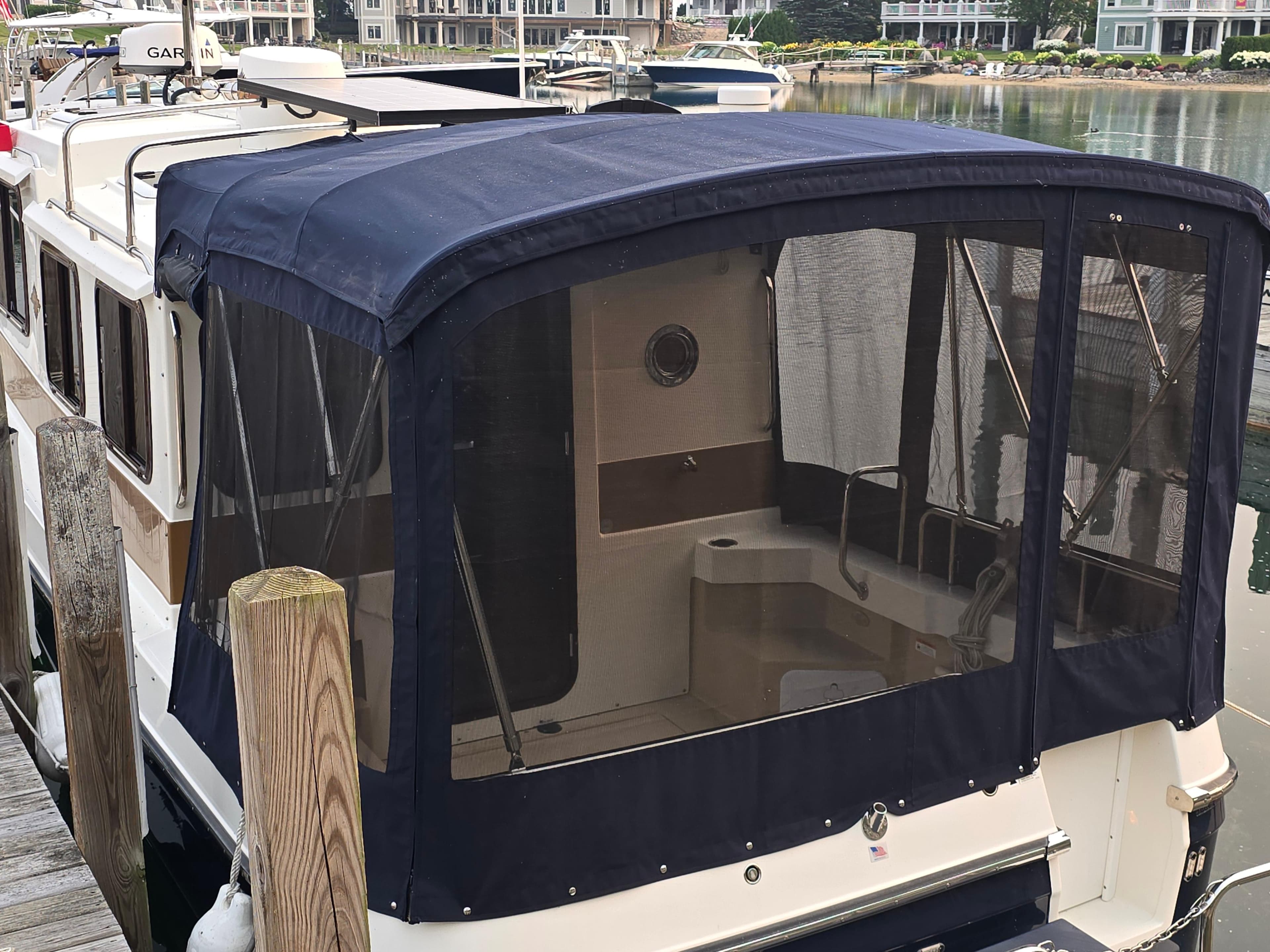 2017 Ranger Tugs R-27 boat with blue canopy docked at marina.