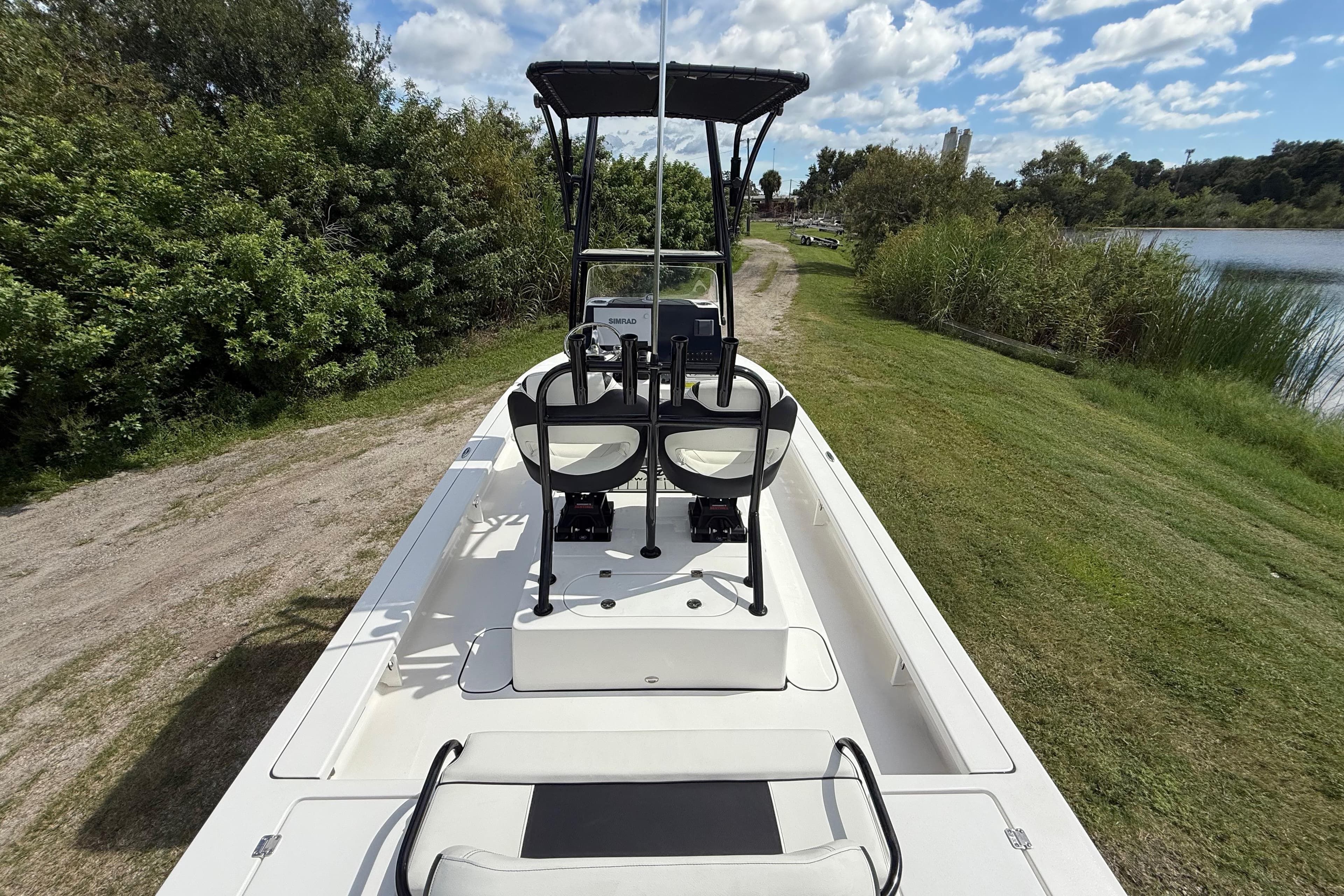 2025 Tidewater 25 TPC Raptor boat on grassy shore near water and trees.