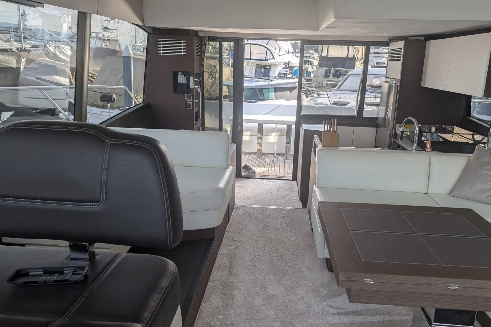 Luxurious interior of 2022 Prestige 590 yacht with modern seating and kitchen area.