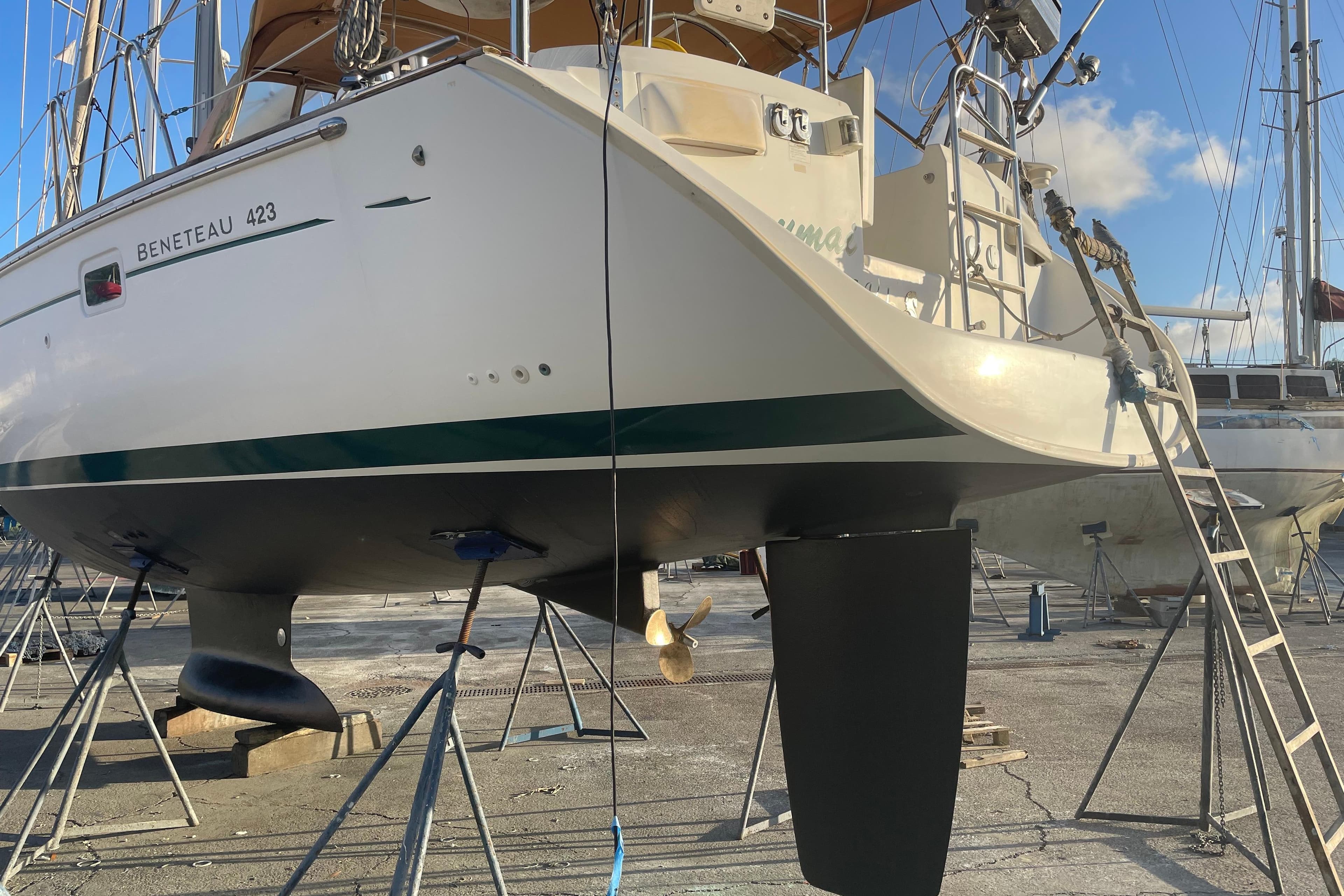 2007 Beneteau 423 sailboat on dry dock, supported by stands, with clear blue sky.