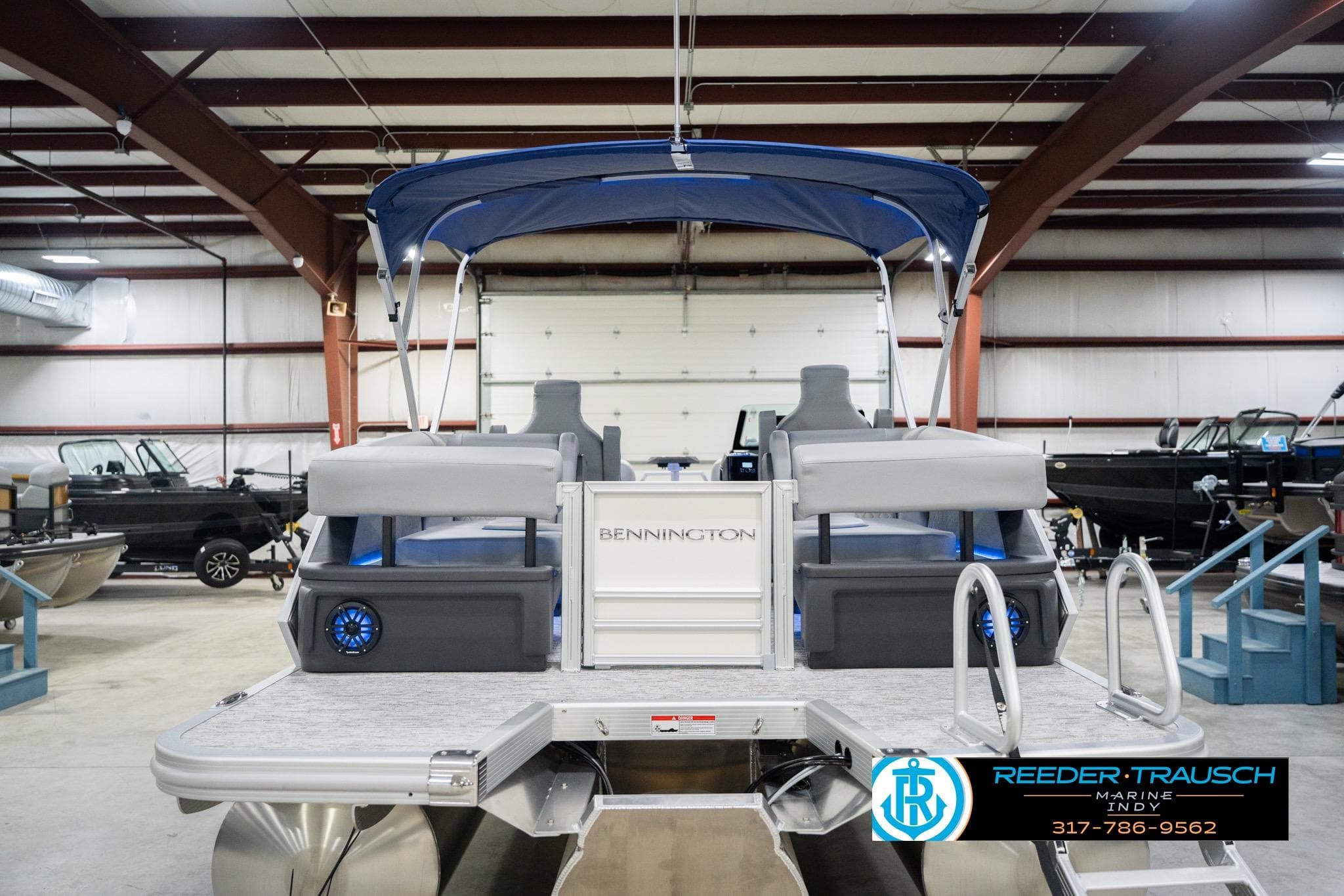 2026 Bennington 24 MOFB pontoon boat in showroom with blue canopy and seating.