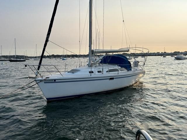 1998 Catalina 320 sailboat on calm water at sunset.