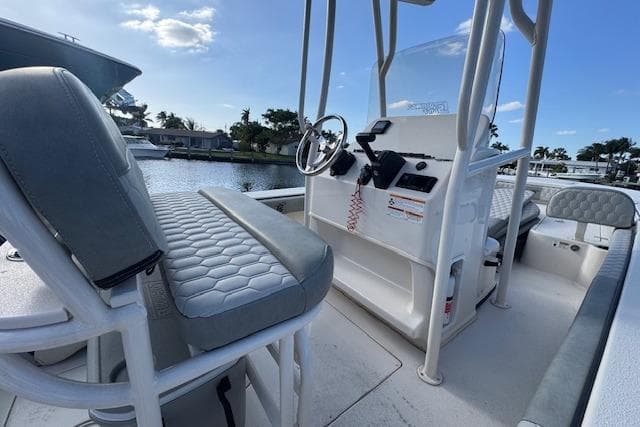 2024 Carolina Skiff 22 Ultra Elite boat interior with seating and console, docked by a waterfront.