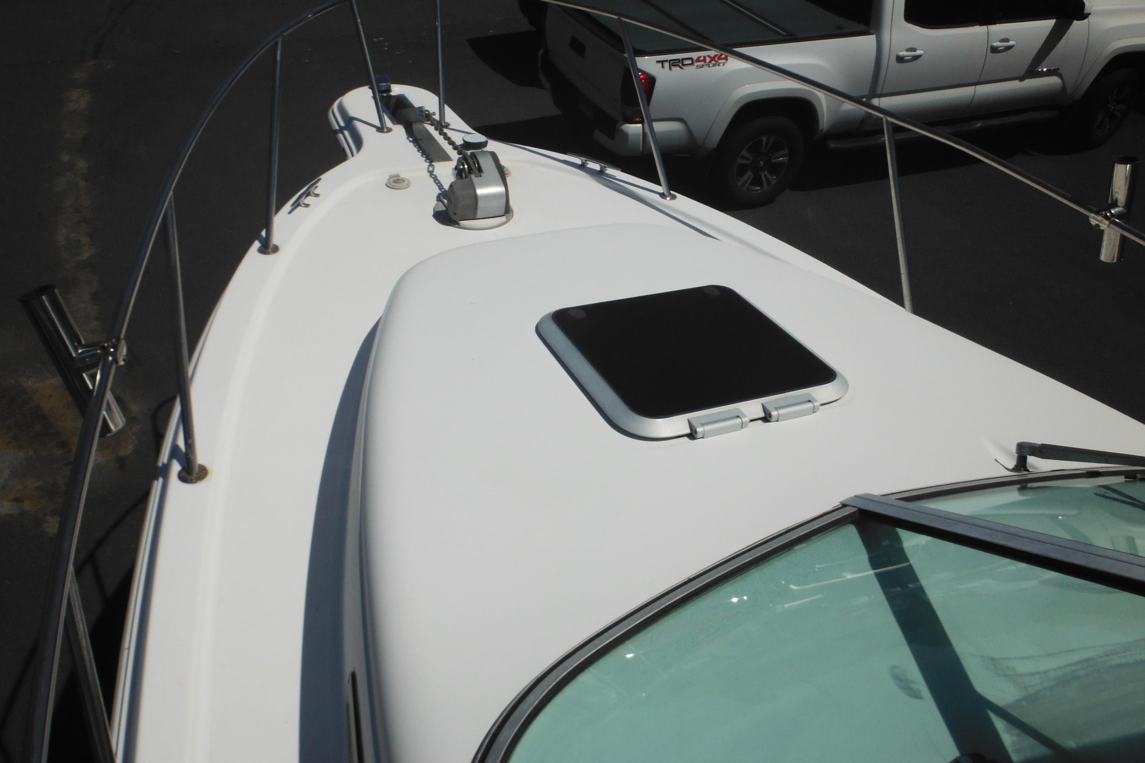 1998 Wellcraft 23 Excel boat deck with hatch and railing, parked near a truck.