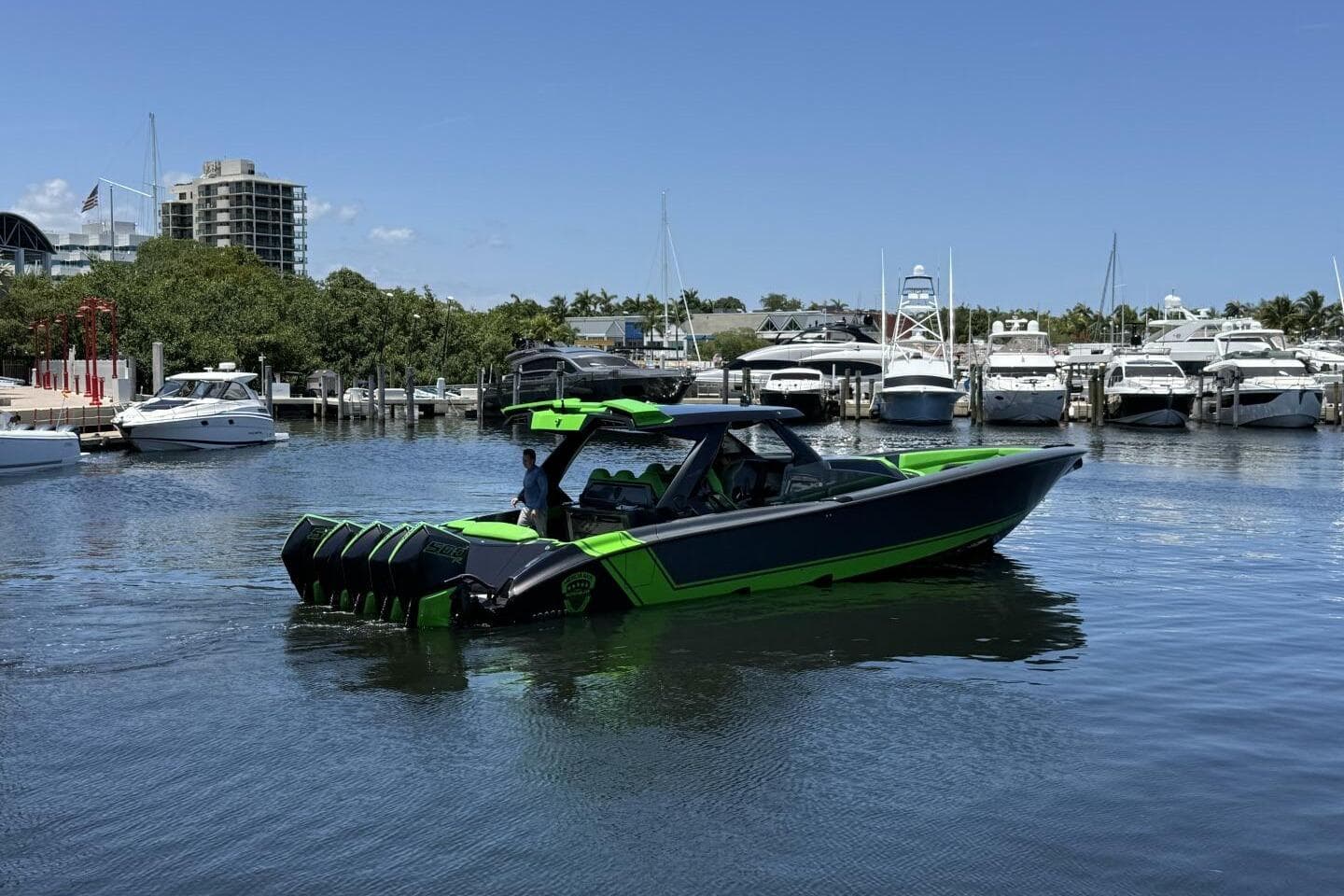 2023 Adrenaline 47 boat in marina, vibrant green and black design, multiple engines, clear blue sky.