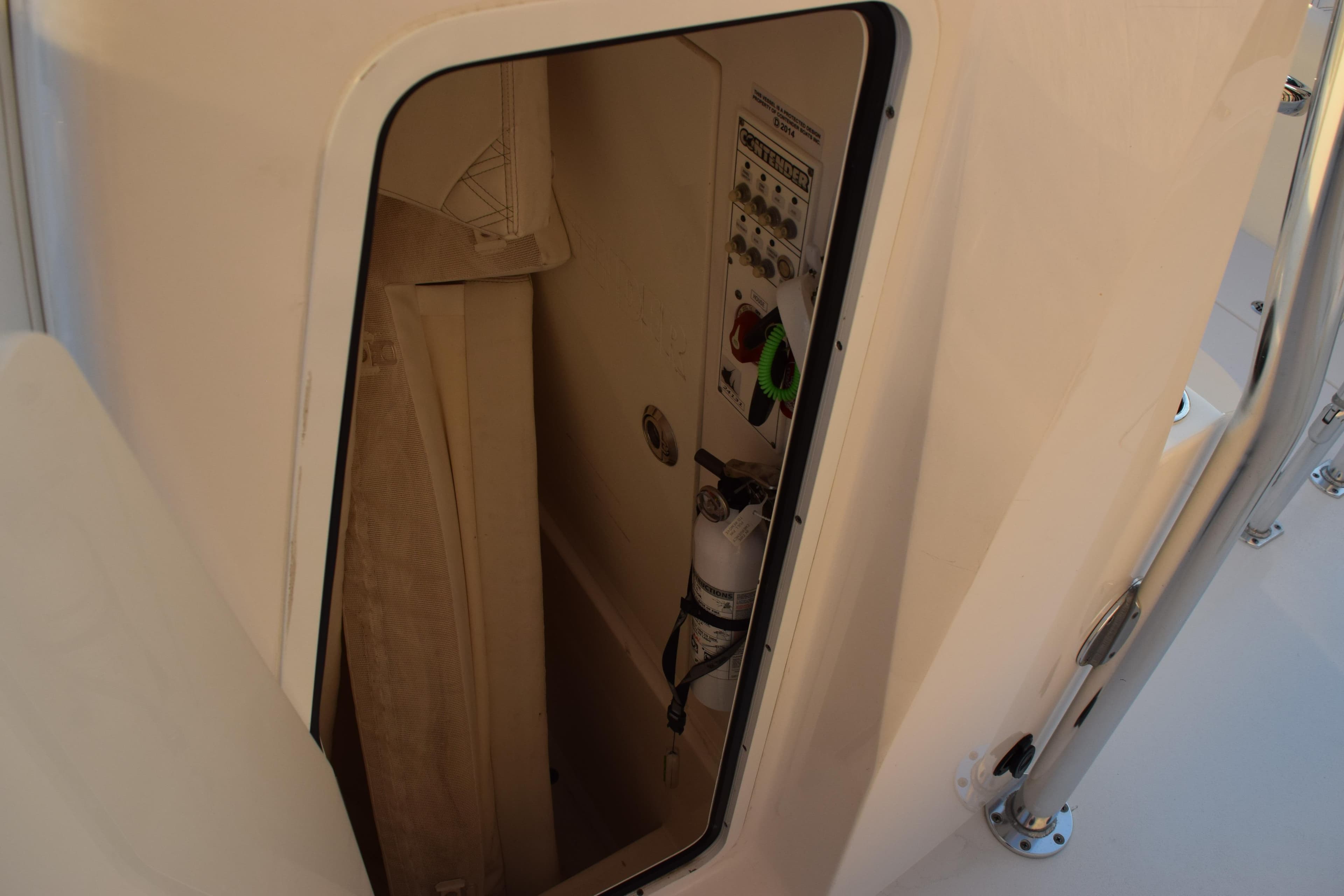 2023 Contender 24 Sport boat interior storage compartment with control panel and fire extinguisher.