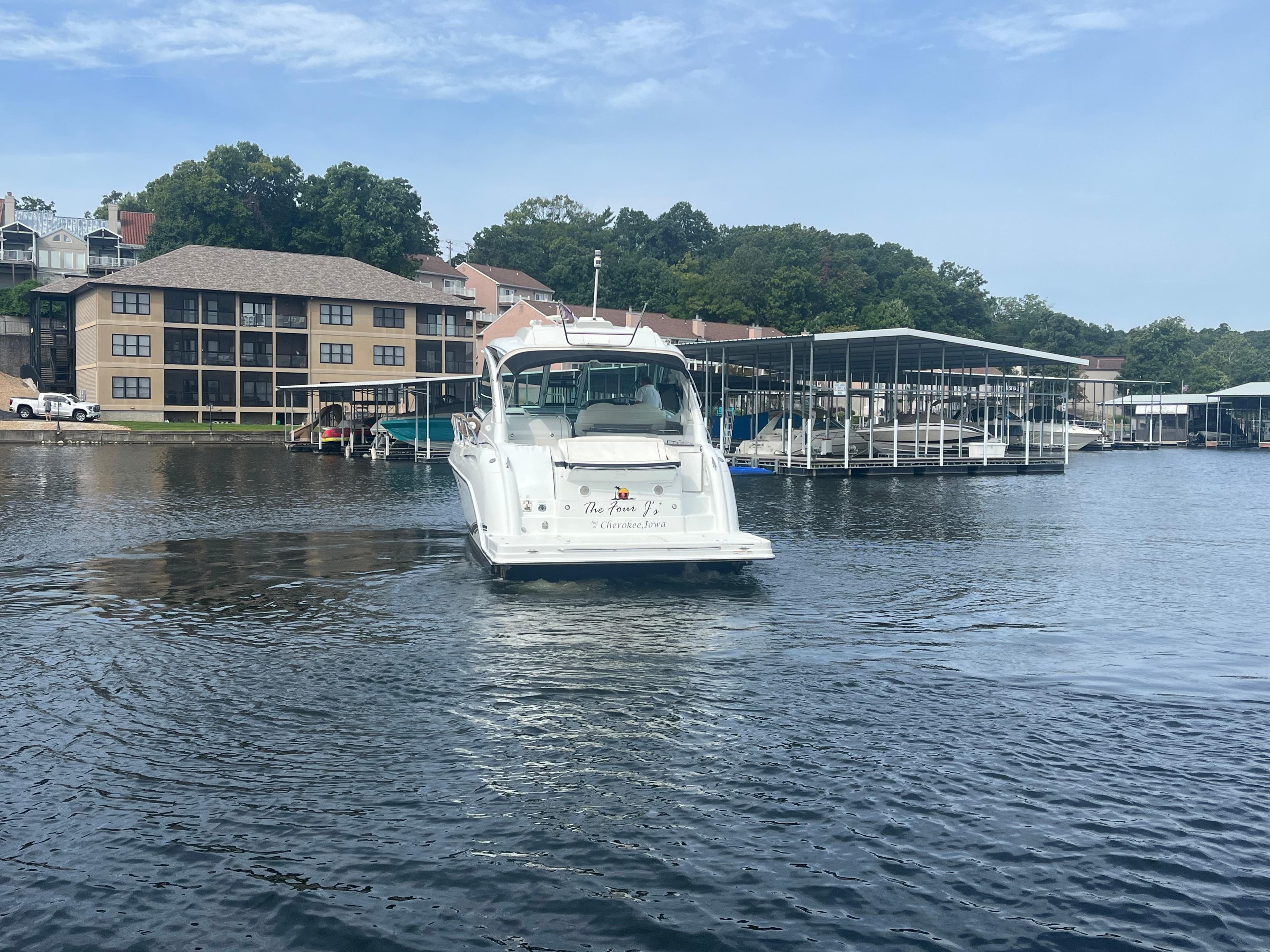 2014 Formula 45 Yacht cruising on a serene lake near waterfront buildings.