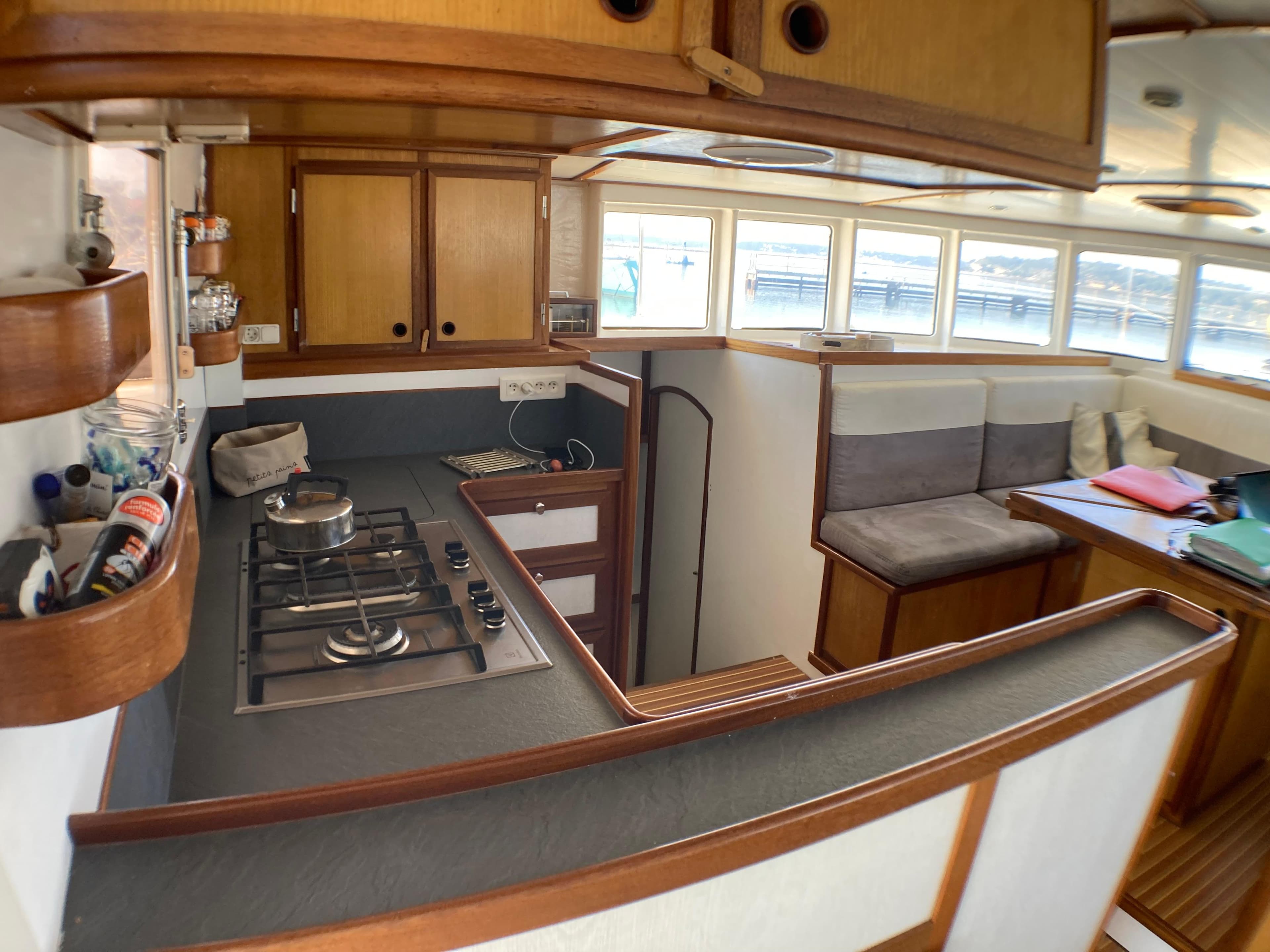 Interior of a 2000 Custom catamaran, featuring a compact kitchen and cozy seating area.