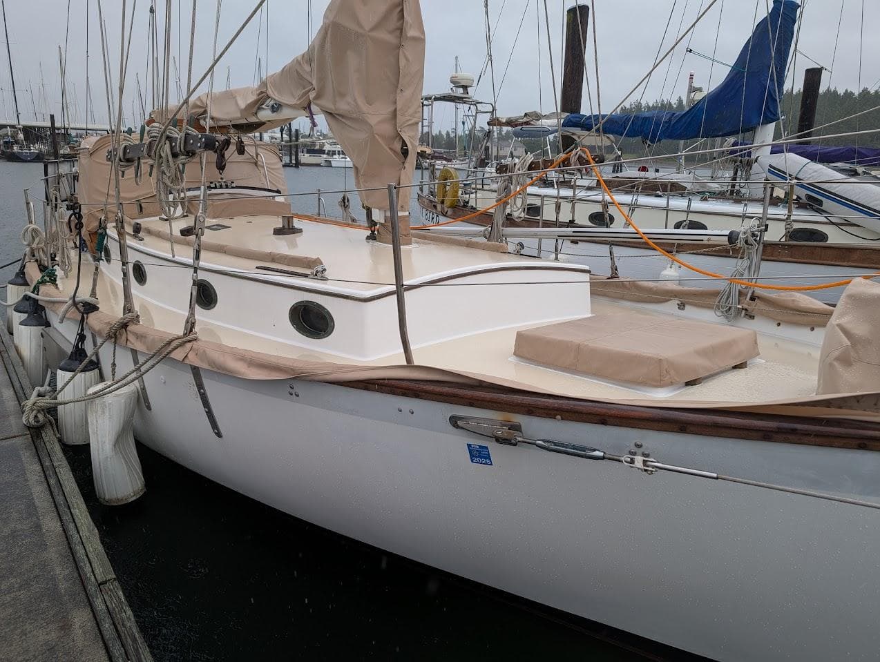 1977 Alajuela 38 Mk1 sailboat docked at marina, covered in beige tarps.