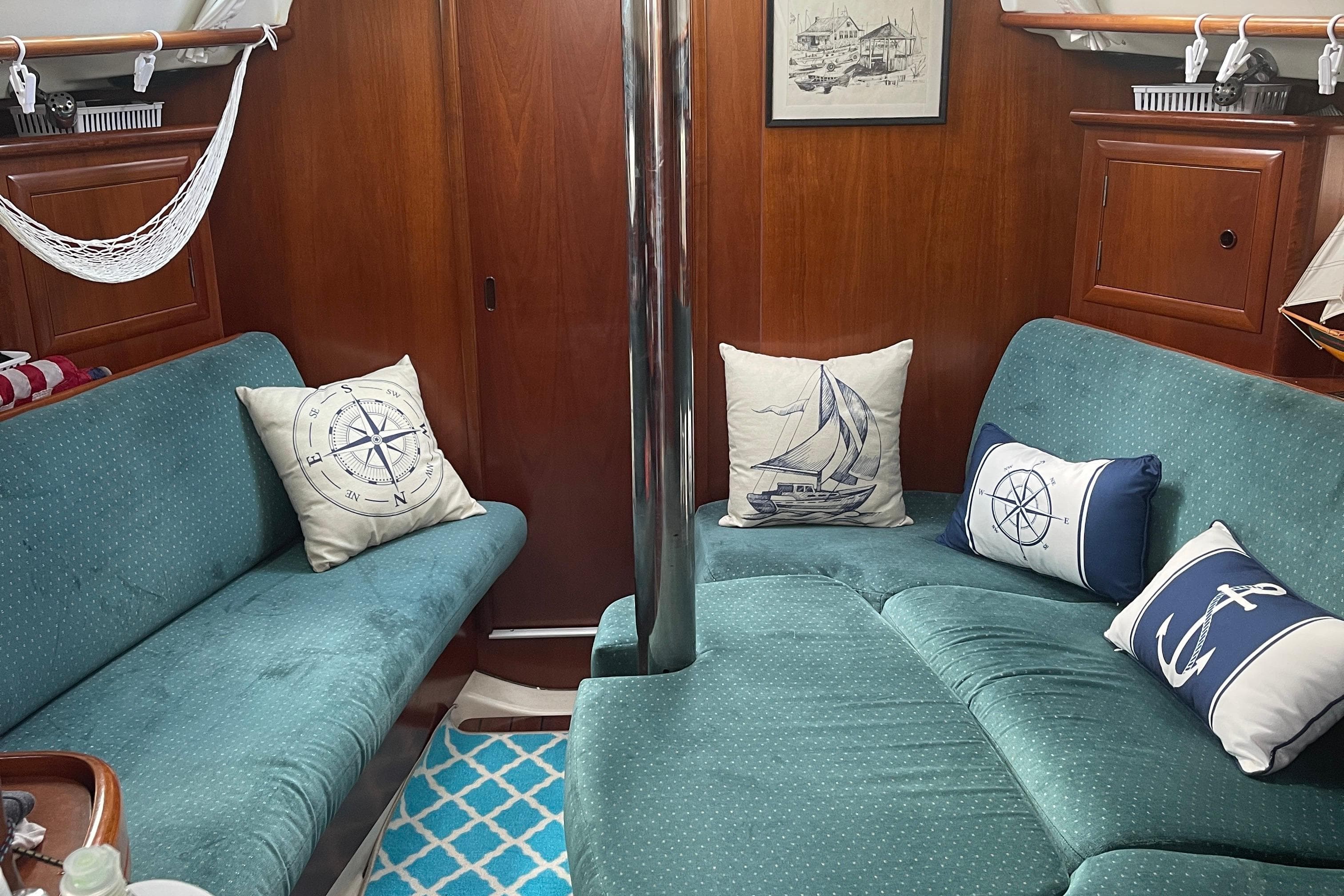 Interior of 2000 Beneteau 331 sailboat with teal seating and nautical-themed pillows.