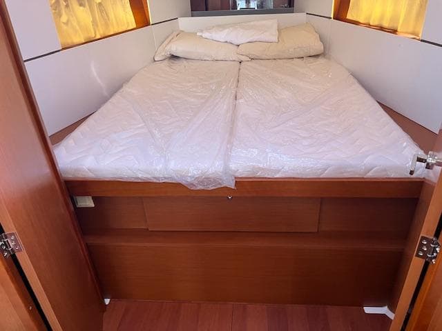 Cabin bed in 2017 Beneteau Oceanis 38.1 yacht, featuring wooden finish and cozy bedding.