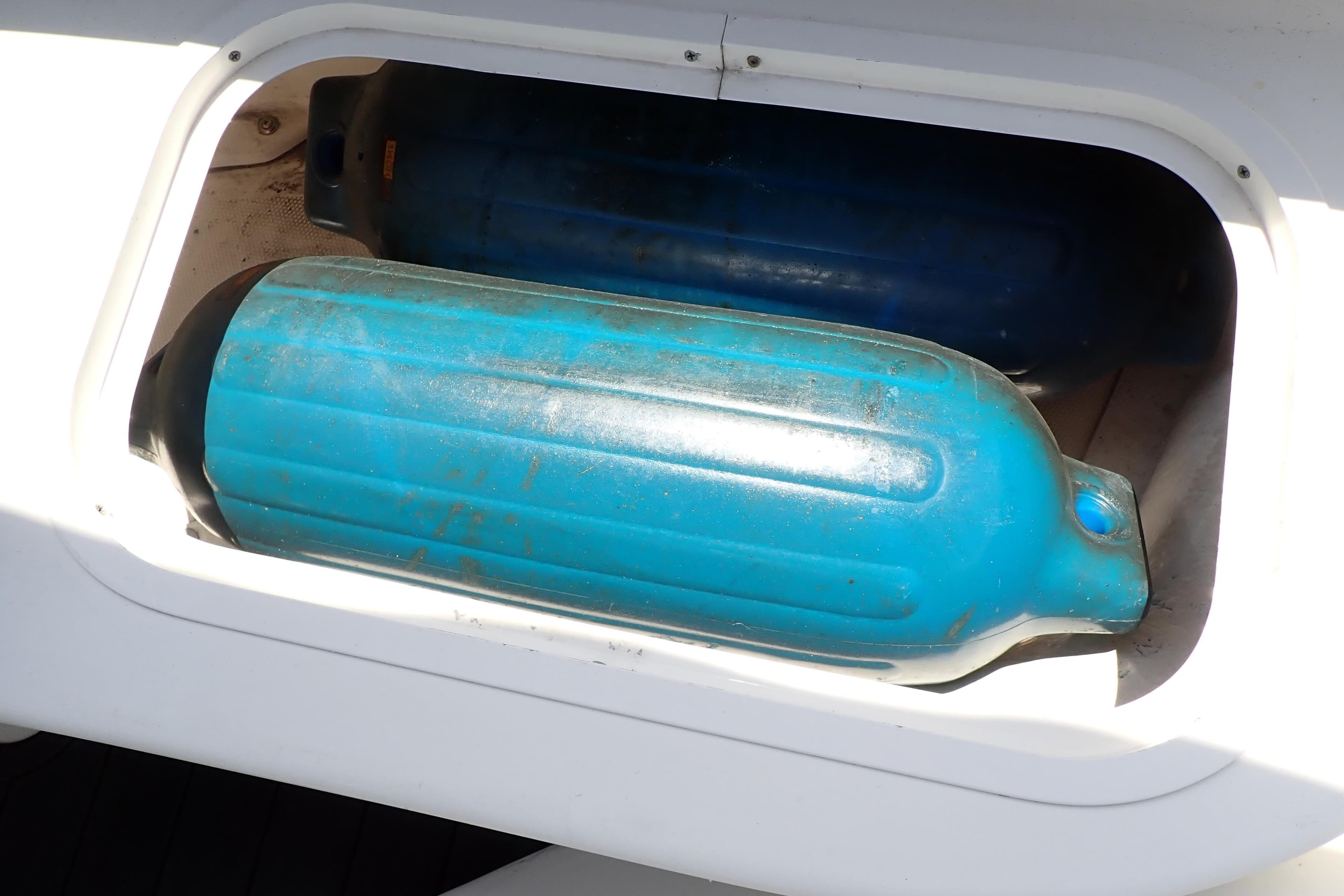 Storage compartment with blue fenders on a 2005 Sea Ray Sundancer 260 boat.