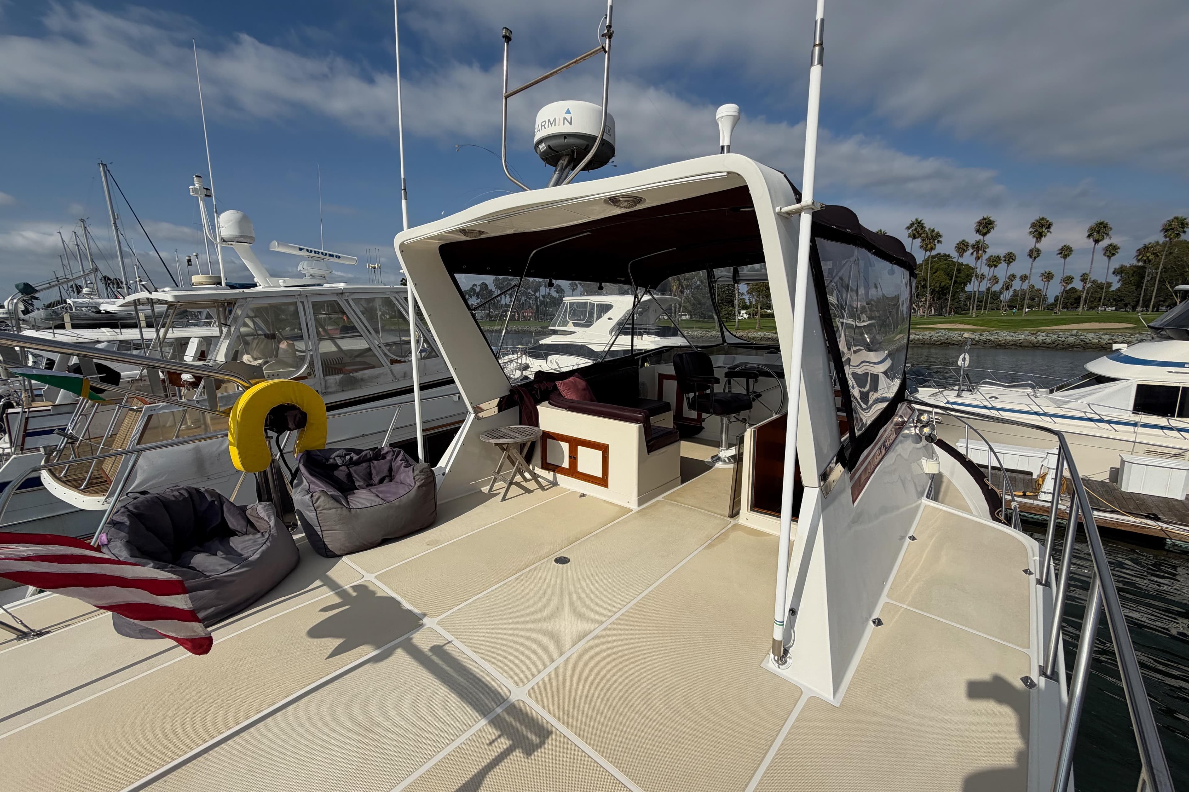 1988 Offshore Yachts 48 Sedan docked, featuring spacious deck and seating area under clear skies.