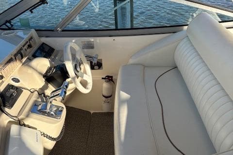1998 Cruisers 3870 Express helm with white seating and steering wheel, overlooking water.