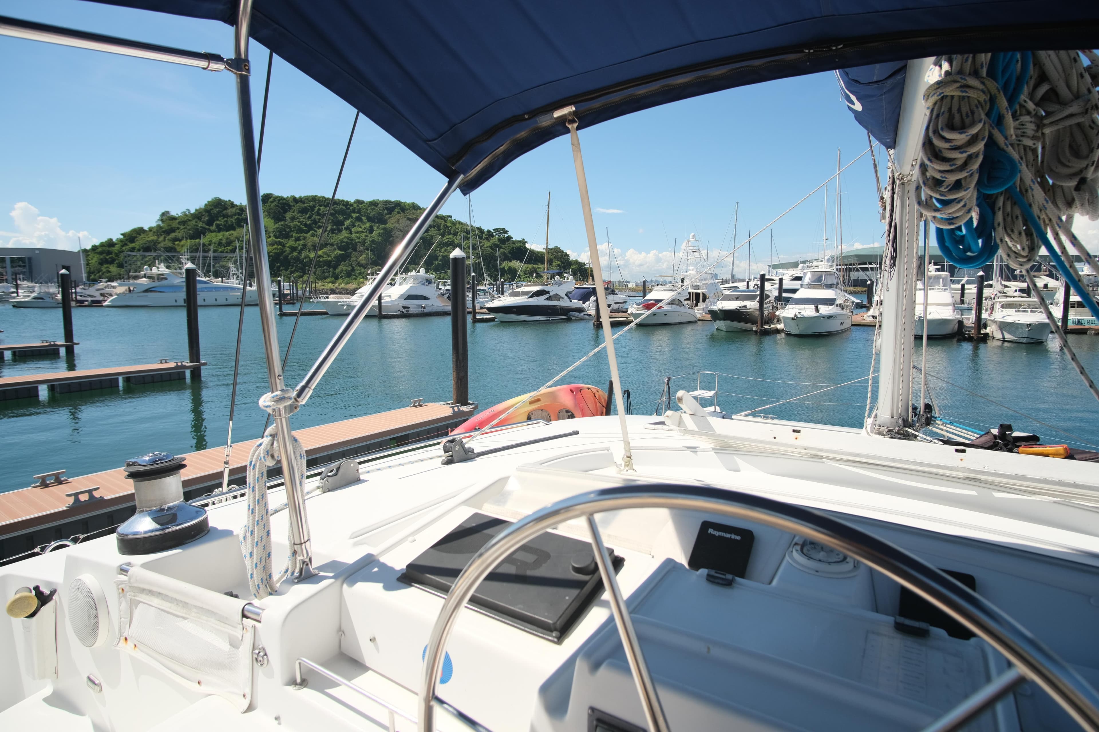 Lagoon 440 catamaran from 2002 docked at a marina with clear blue skies.