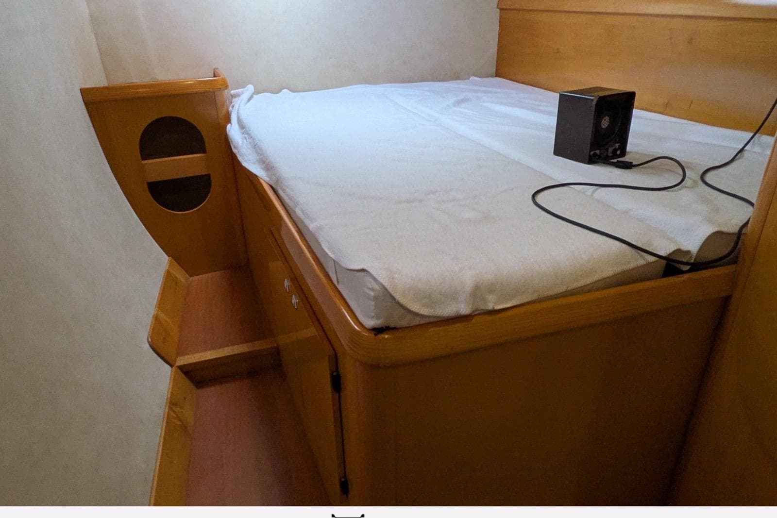 Cozy cabin interior of 2006 Fountaine Pajot Belize 43 catamaran with wooden bed and speaker.