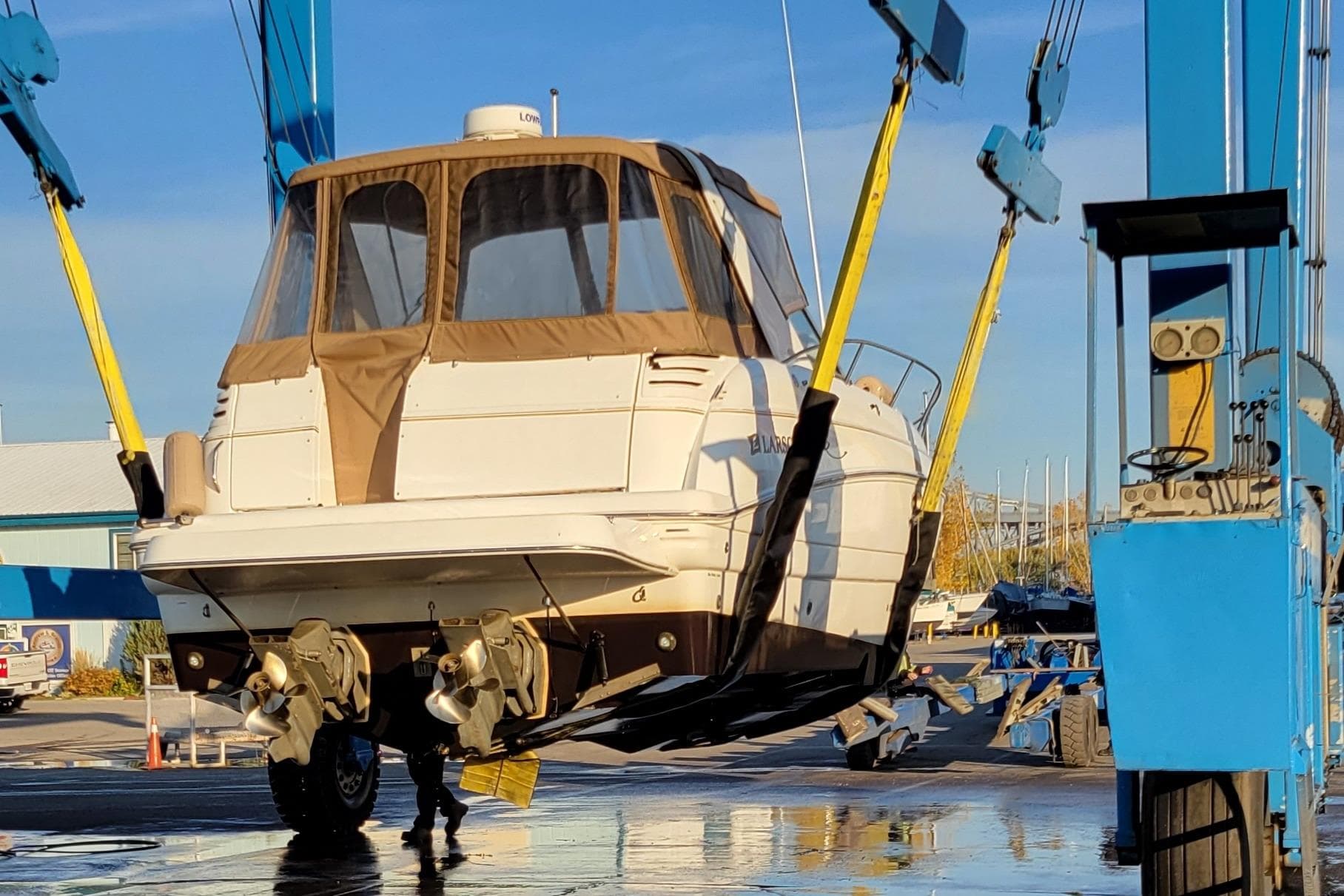2002 Larson 330 boat being lifted by a crane at a marina.