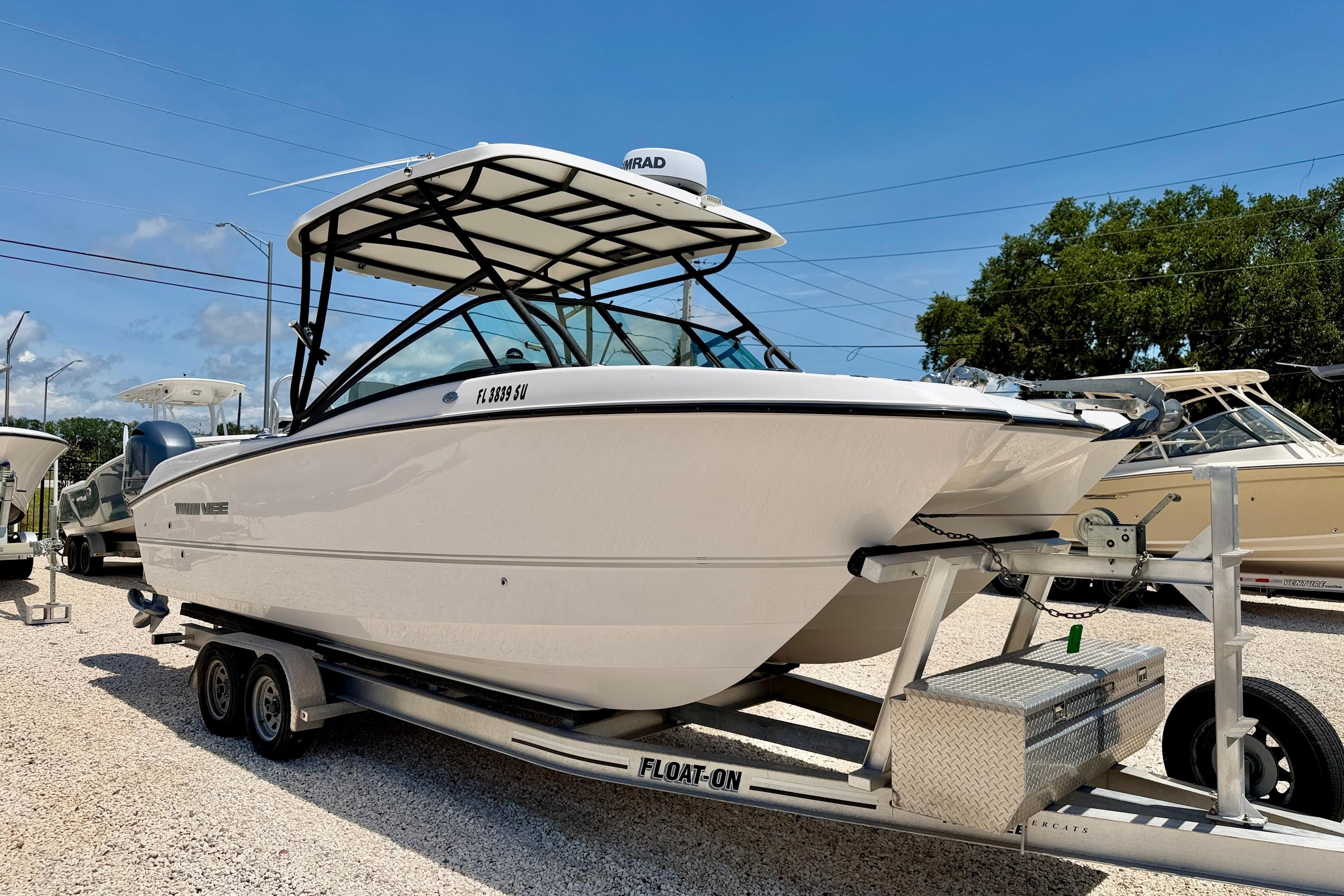 2021 Twin Vee 240 GFX DC boat on trailer, displayed outdoors under clear sky.