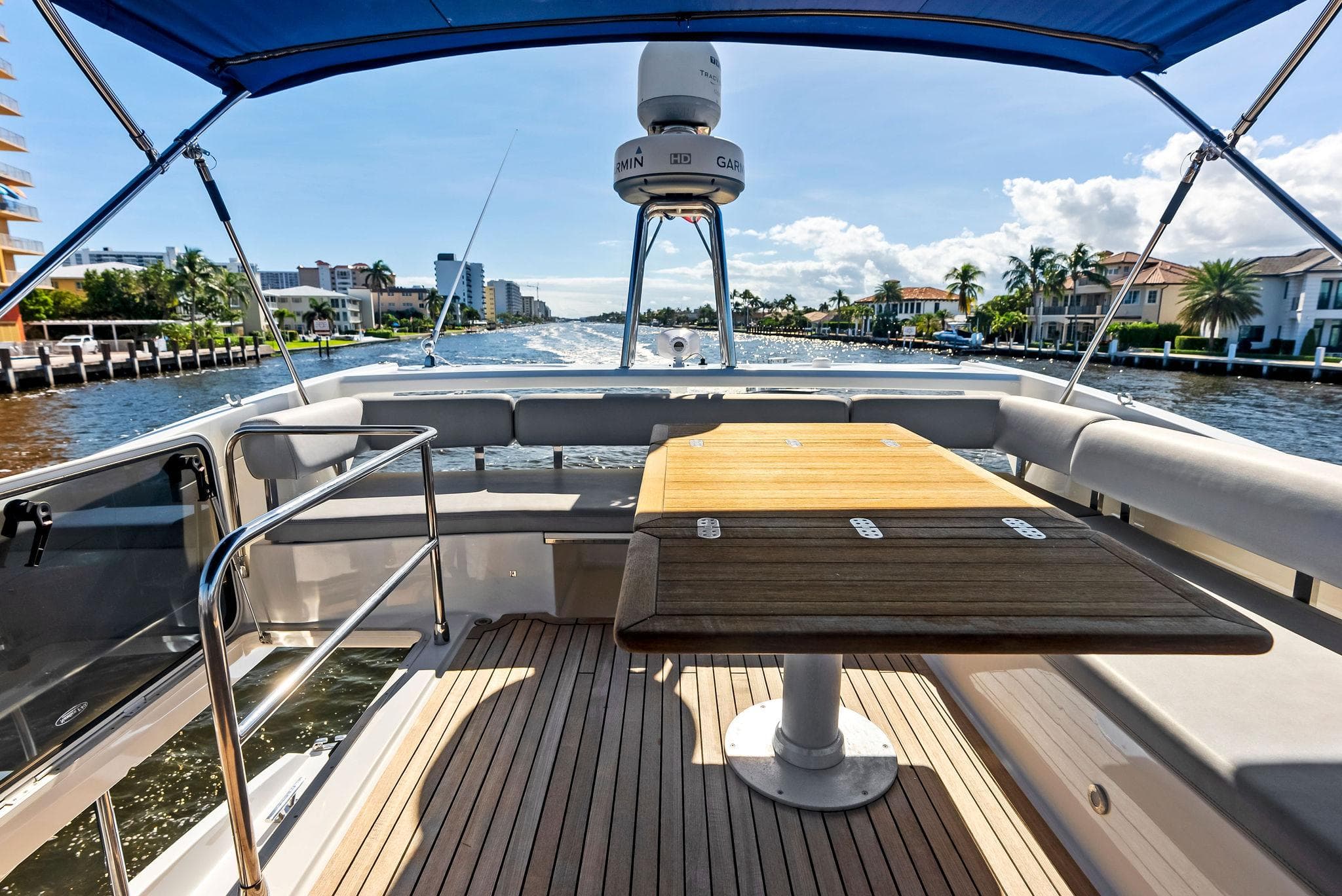 Flybridge view of 2013 Absolute 55 FLY yacht with wooden table and waterfront scenery.