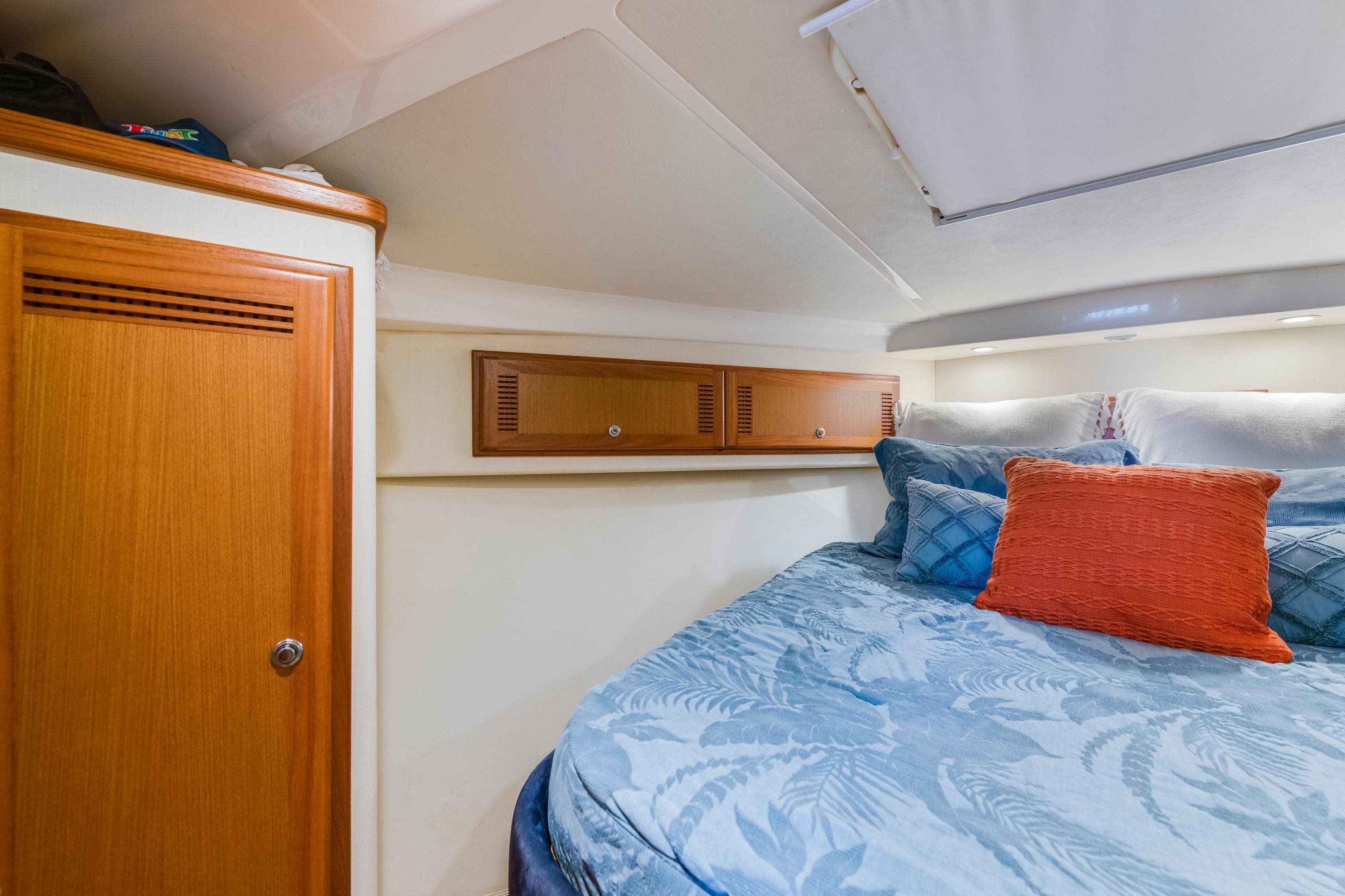 Cozy cabin interior of 2005 Cabo 35 Flybridge with blue bedding and wooden storage.