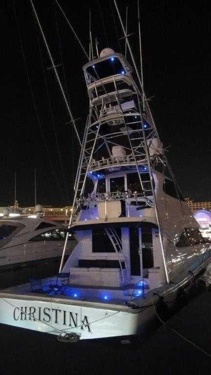 2004 Riviera 58 Enclosed Flybridge yacht at night with blue lights.