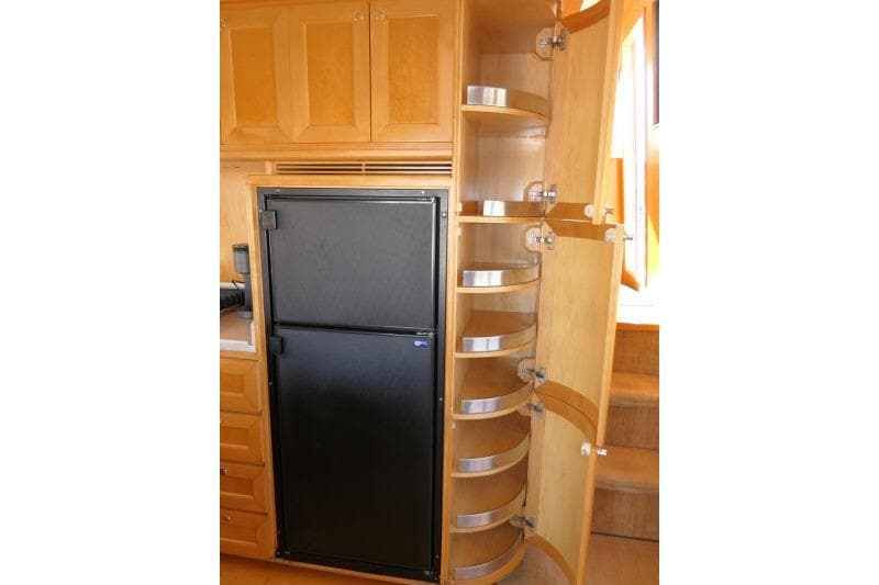 Interior of 1999 Hampton 490 Pilothouse with fridge and curved wooden storage shelves.