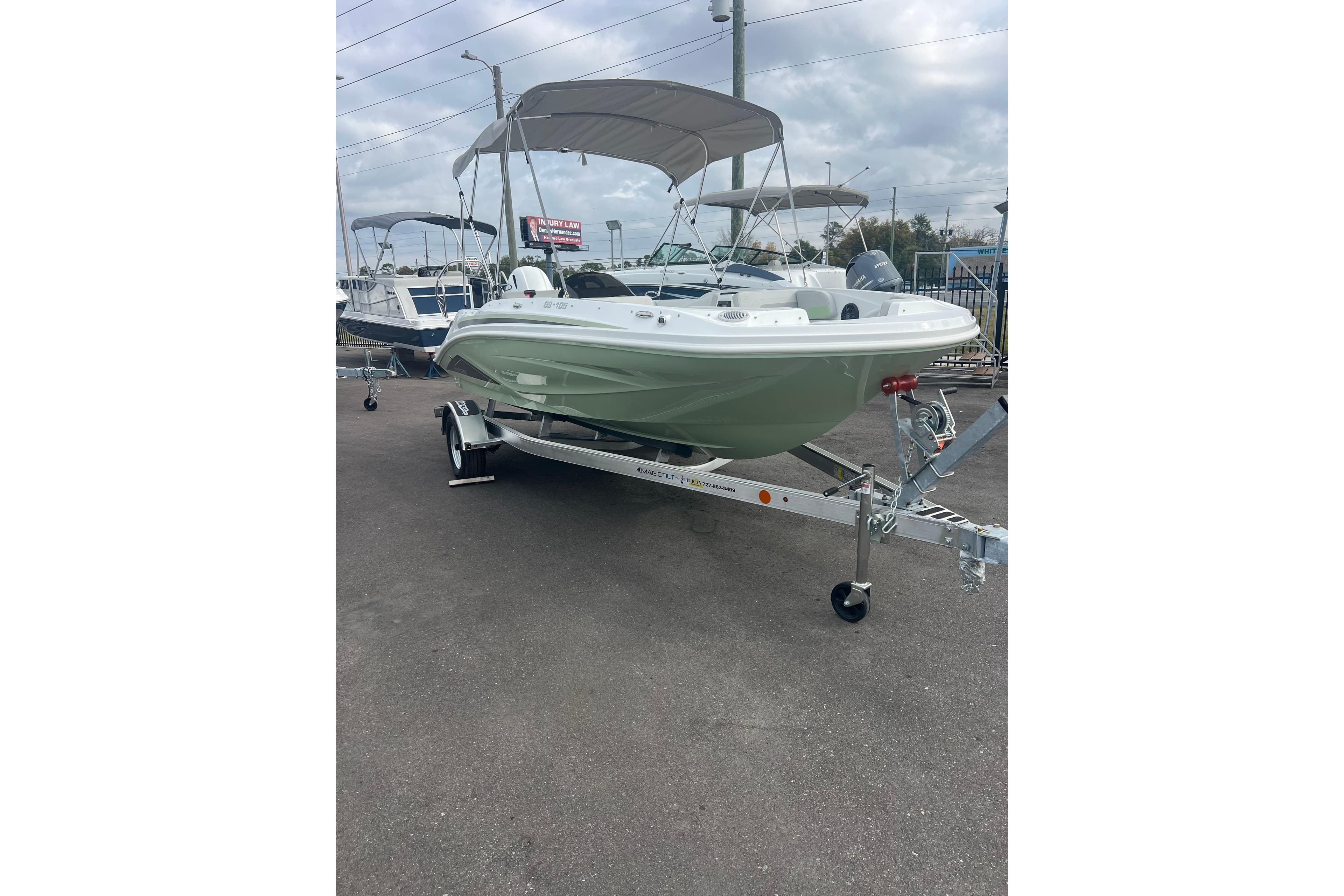 2026 Hurricane SunDeck Sport 185 OB boat on trailer, parked outdoors.