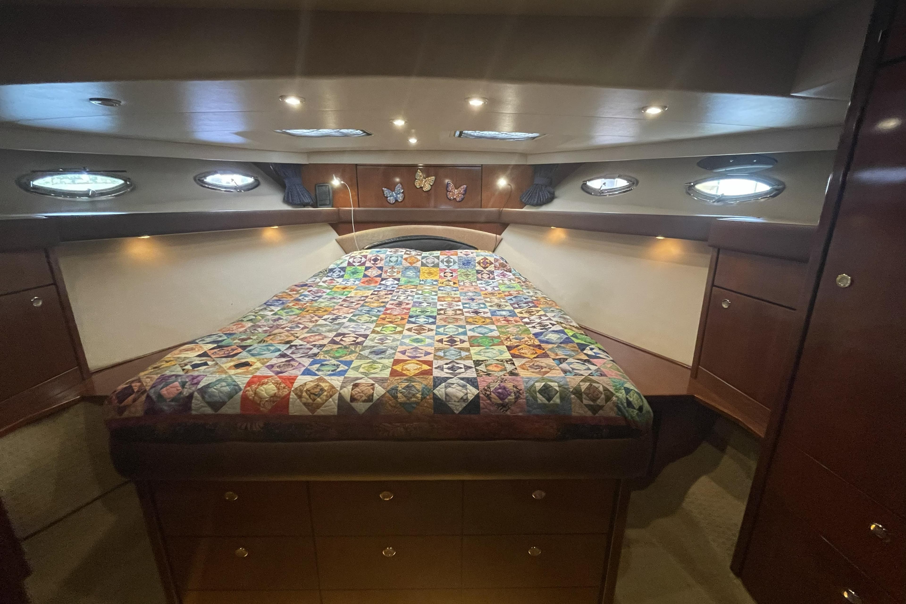 Luxurious 2008 Meridian 490 Pilothouse cabin with colorful quilt and elegant wood finish.