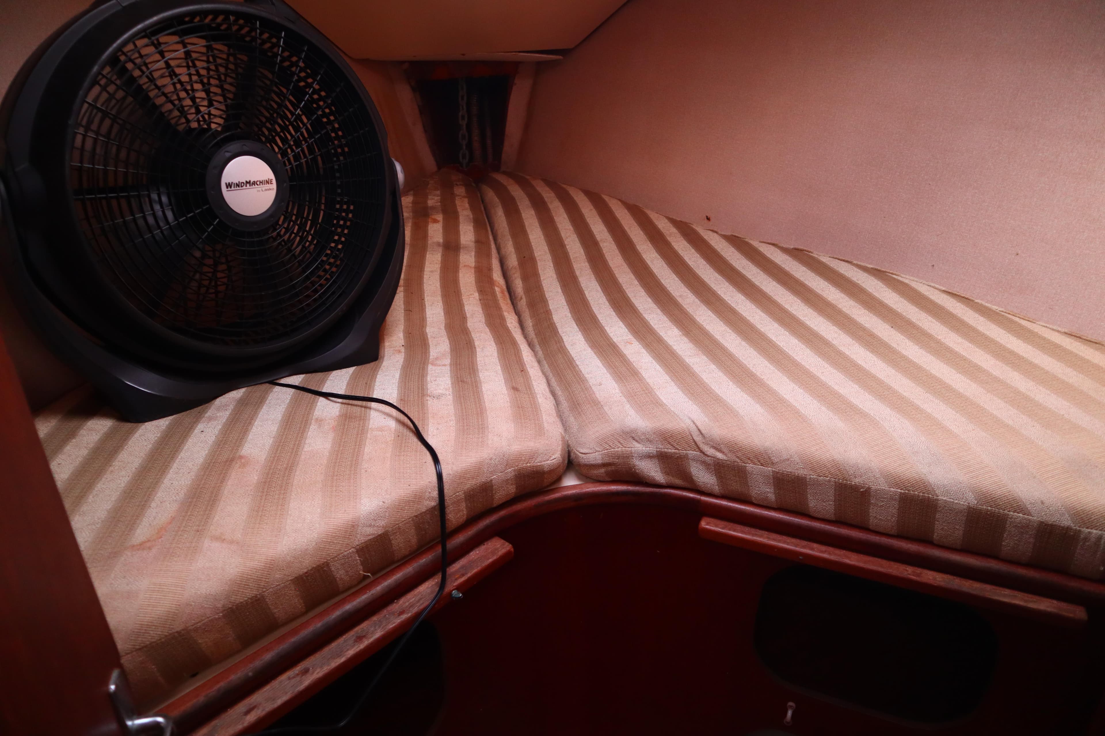 1997 Hunter 37 boat cabin with striped bedding and a fan.