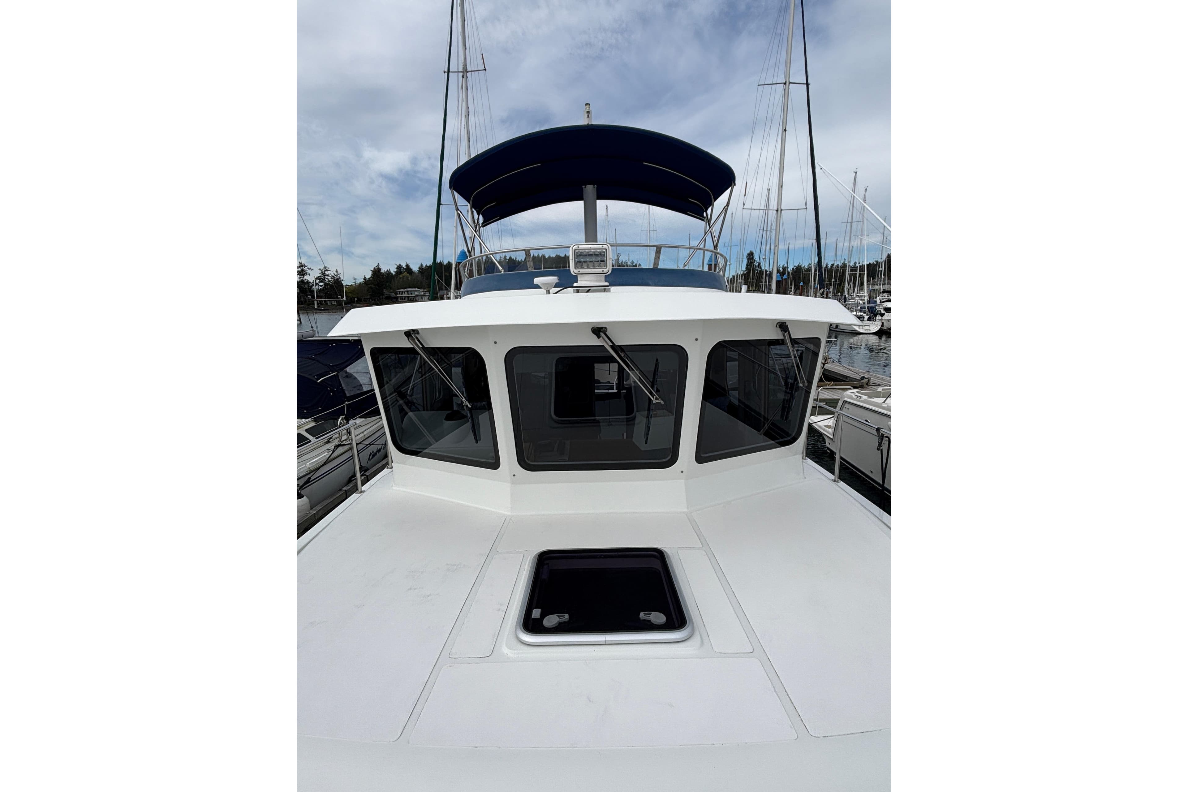 2006 Pilothouse Rockport Fast Trawler with blue canopy, docked at marina.