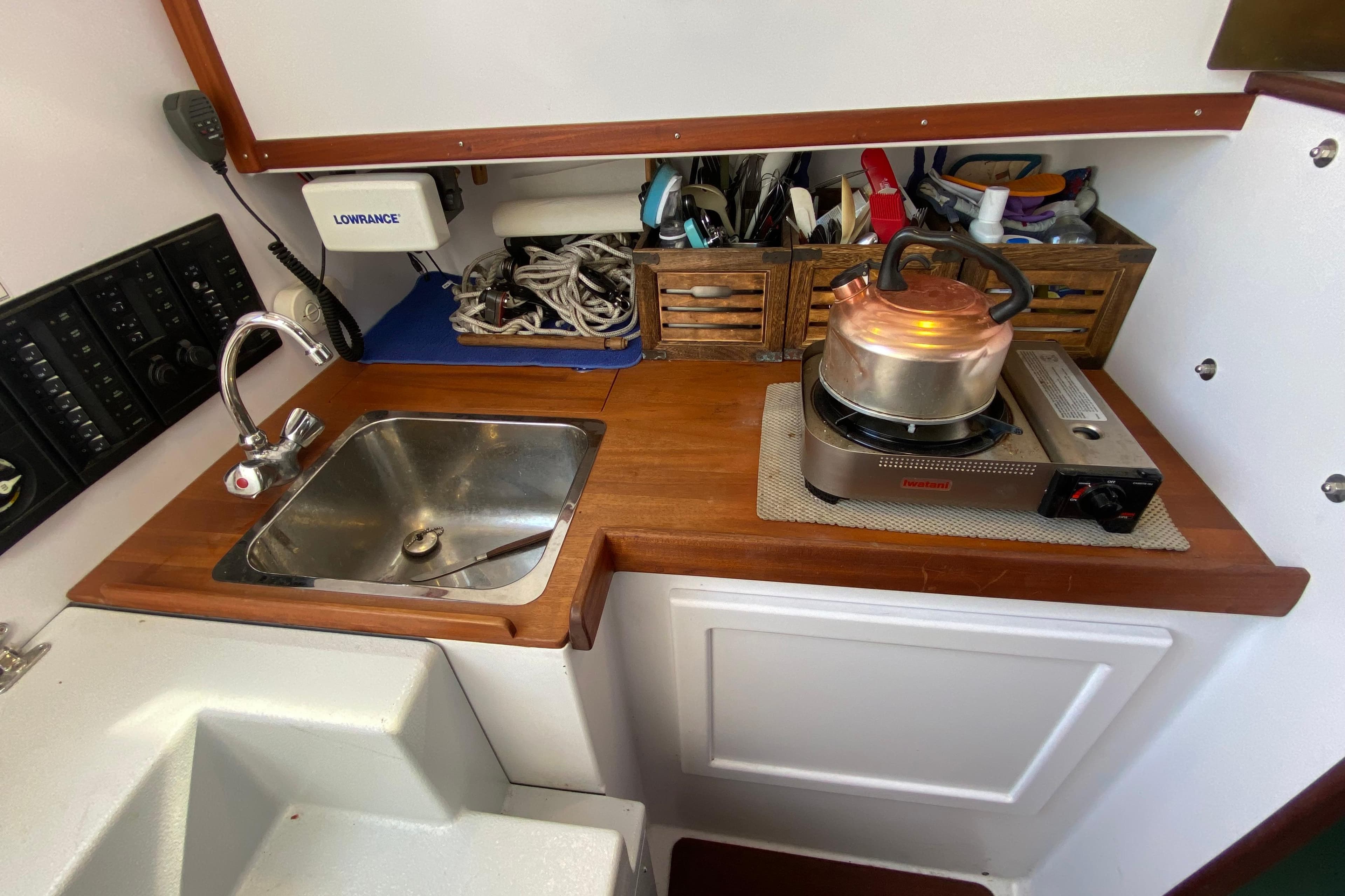 Compact boat kitchen with sink, stove, and storage on a 2013 Devlin Onyx model.