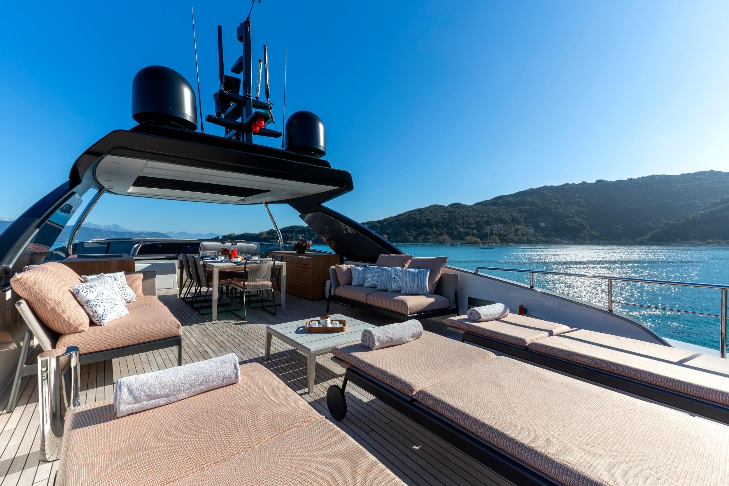Luxurious 2024 Sanlorenzo SL86 yacht deck with sun loungers and dining area, overlooking serene waters.