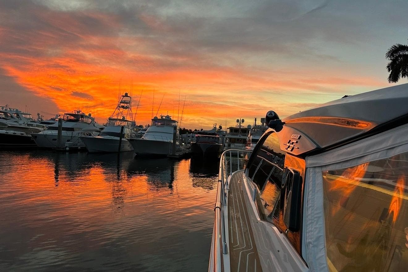 Azimut Atlantis 45 yacht at sunset in marina, reflecting vibrant orange sky.