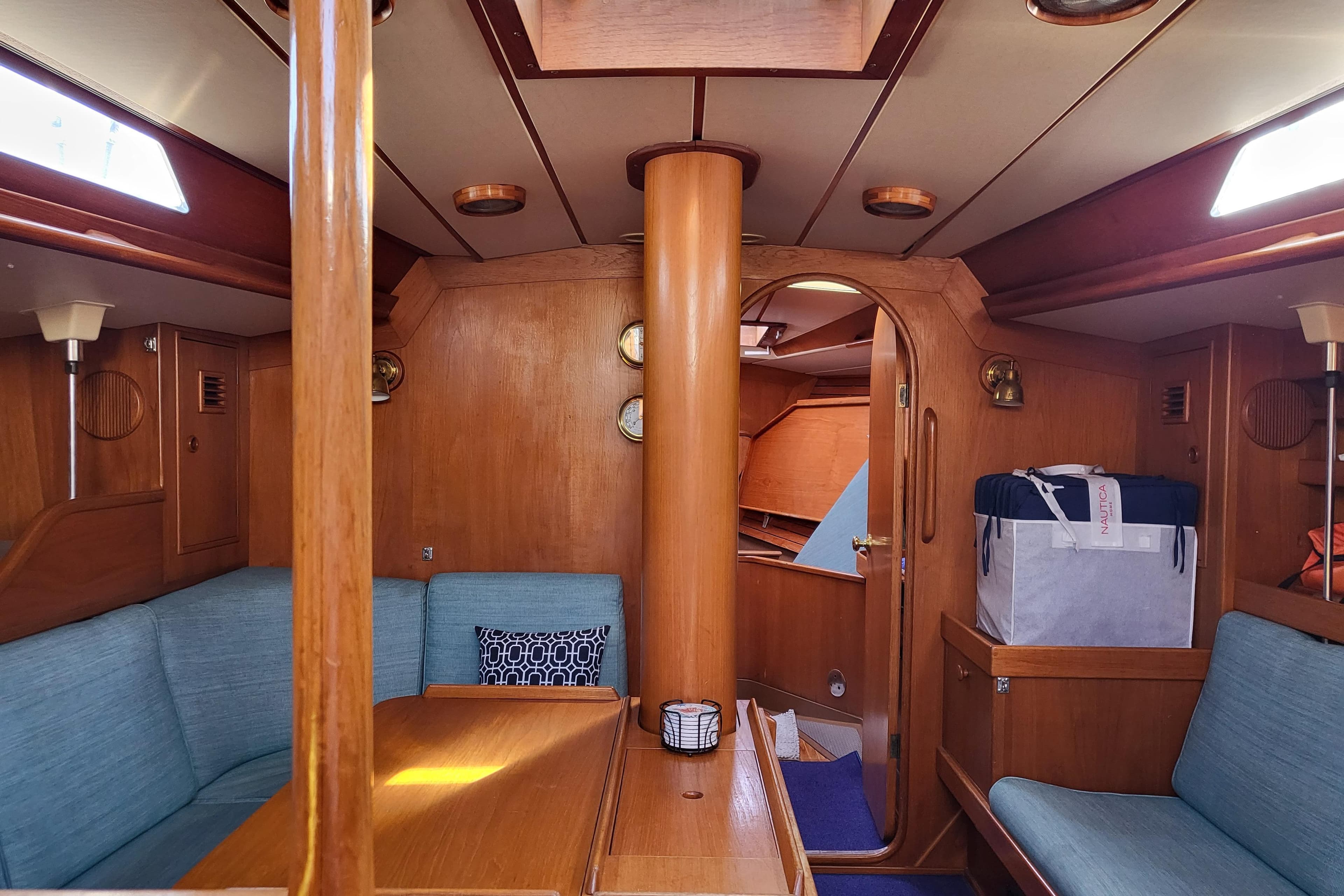 Interior of 1985 Swan 46 yacht with wooden furnishings and blue seating.